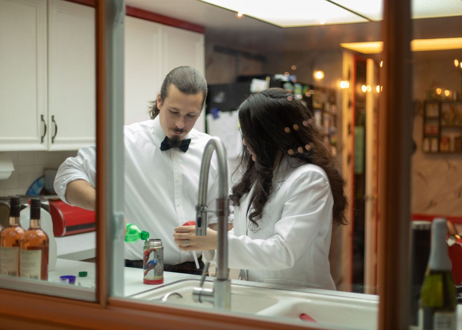 Two people in white working together in a kitchen setting.