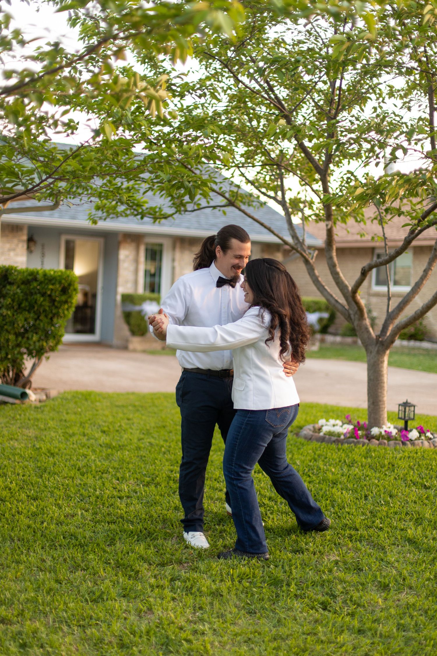 Couple dancing together on lawn in coordinated white and navy outfits.