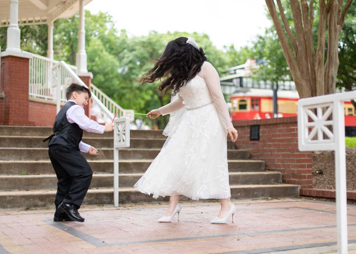 Joyful dance scene between wedding party members on brick steps outdoors.