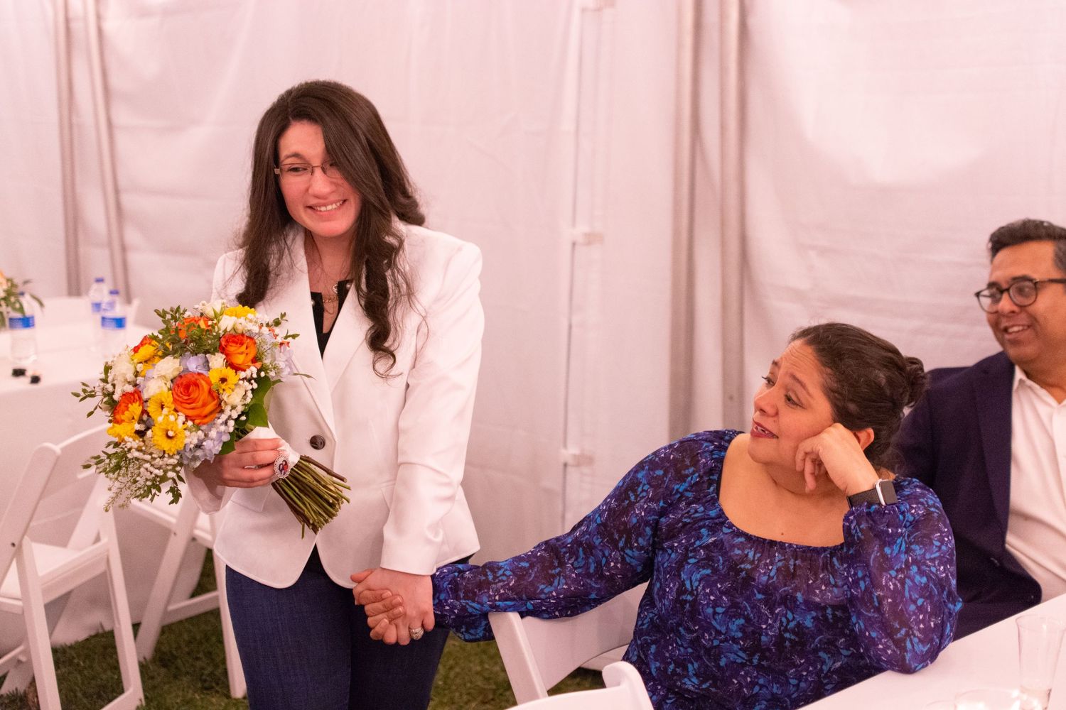 Wedding reception scene with guests and colorful sunflower arrangements.