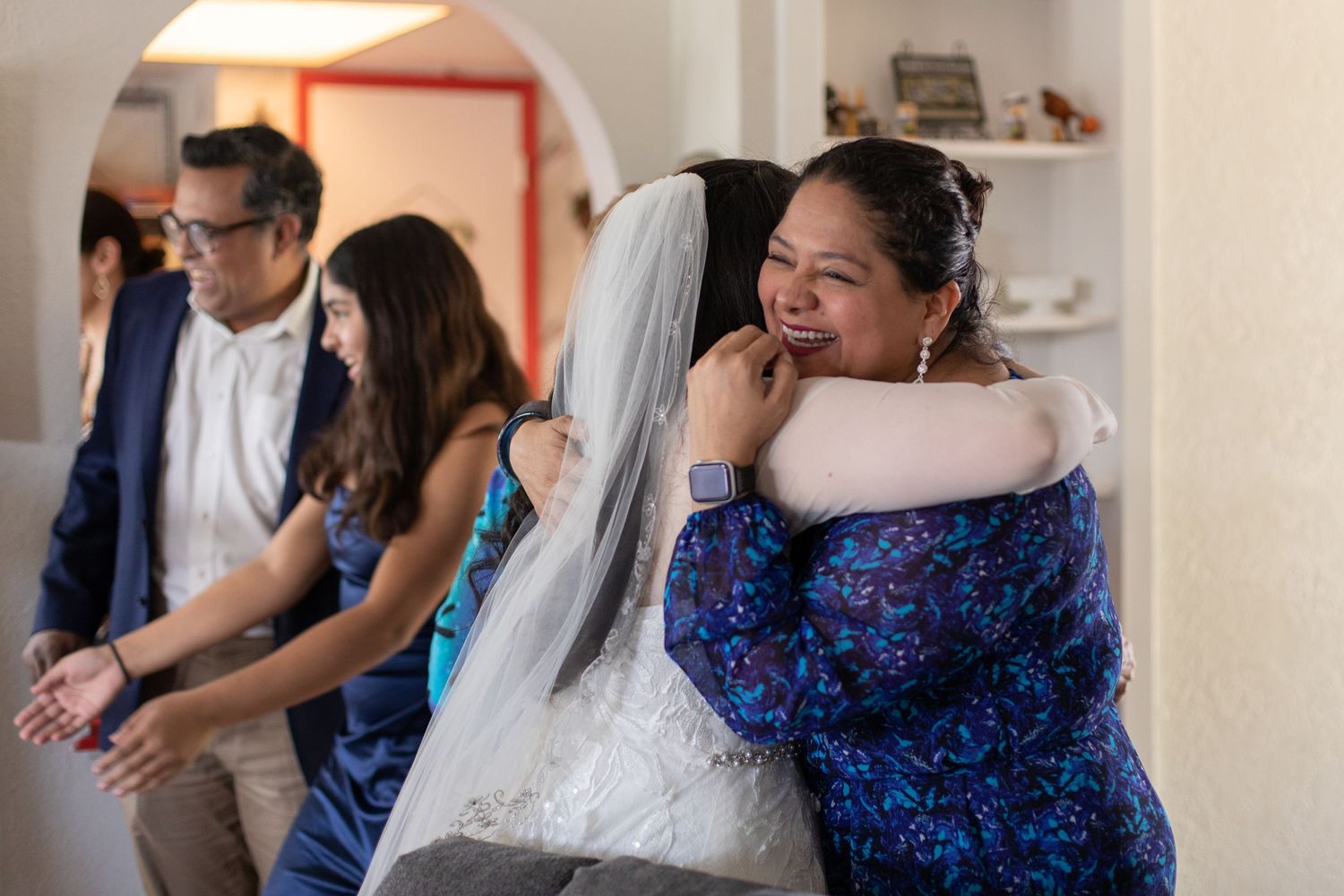 Wedding celebration with people embracing in a festive indoor setting.