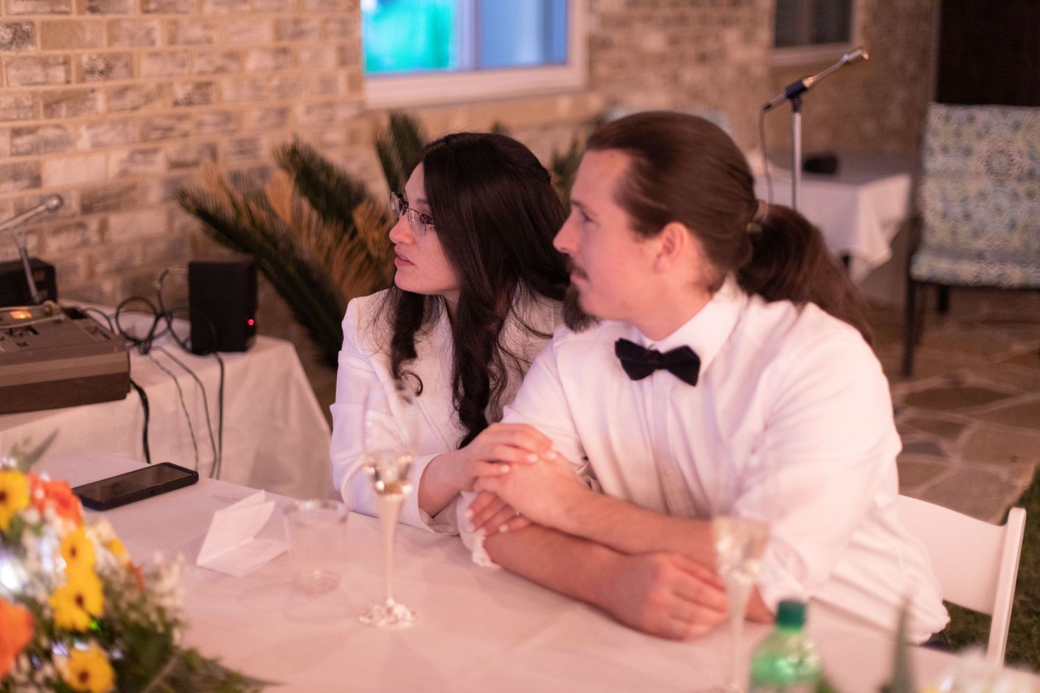 A couple sharing a moment at their backyard wedding reception table decorated with vibrant flowers.