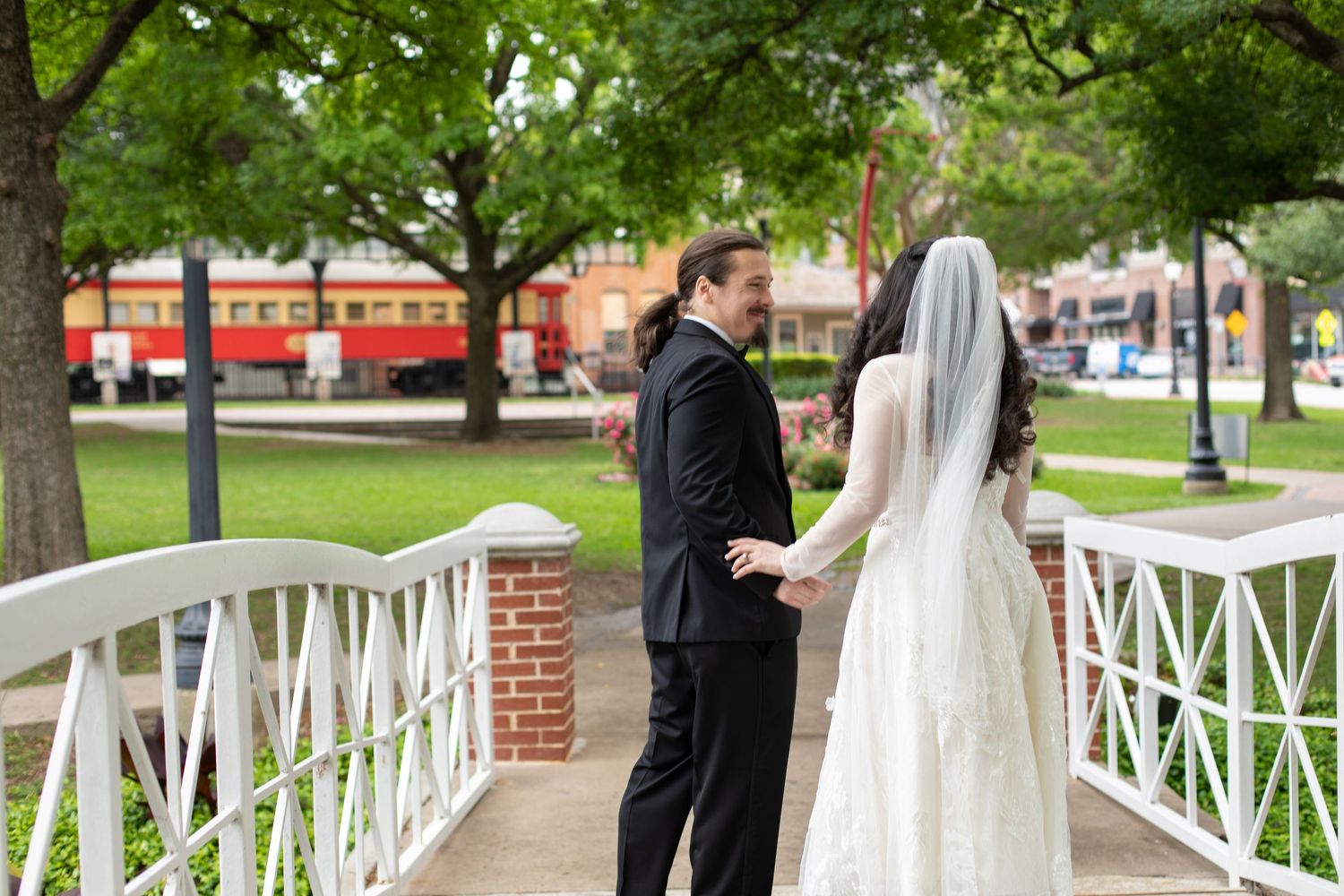 Two people share a romantic embrace on a white bridge during their wedding photoshoot.