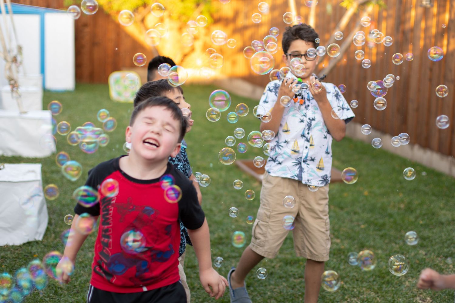 Children playing with bubbles in a backyard during golden hour.