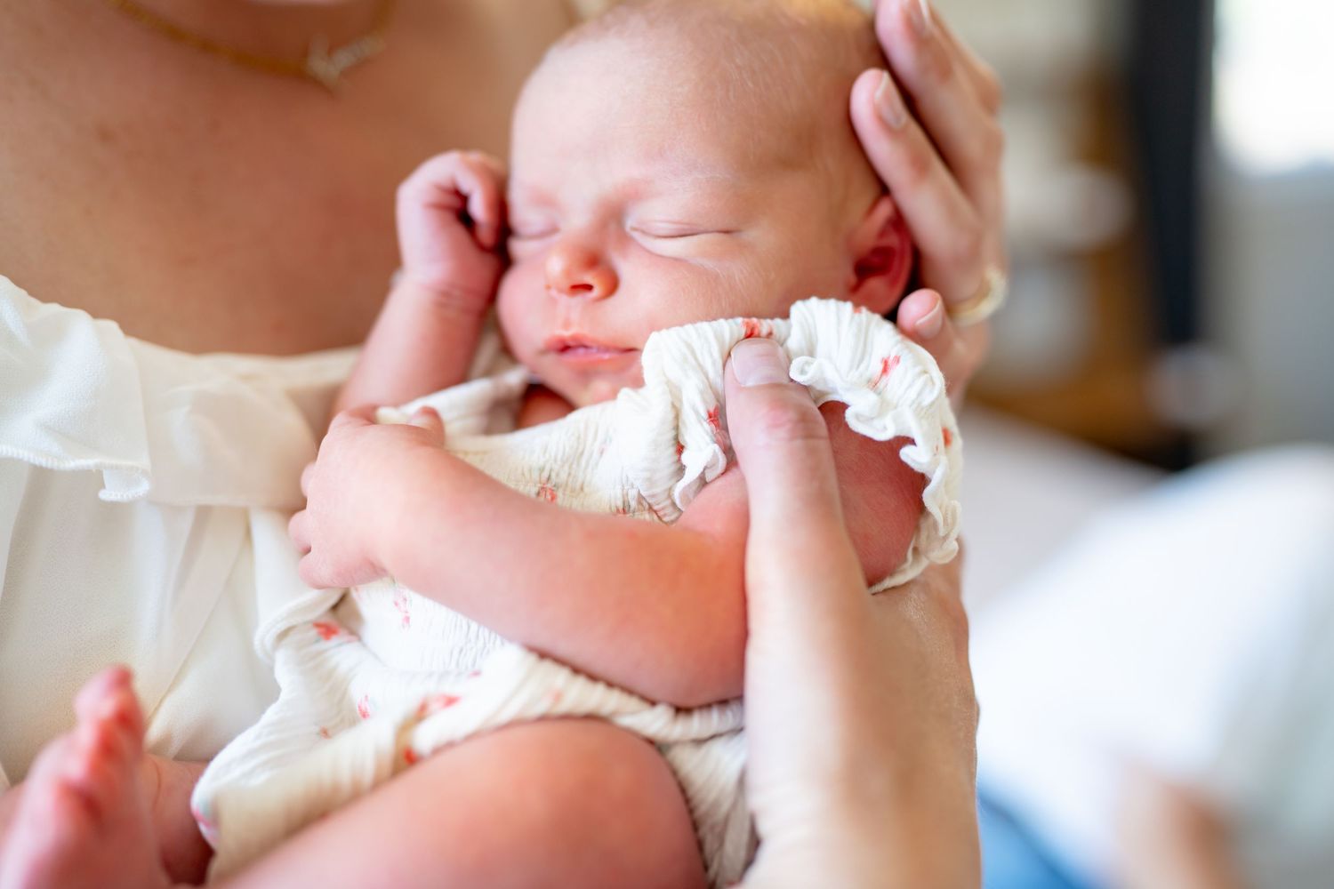 Newborn baby sleeping peacefully while being held gently in mother's arms.