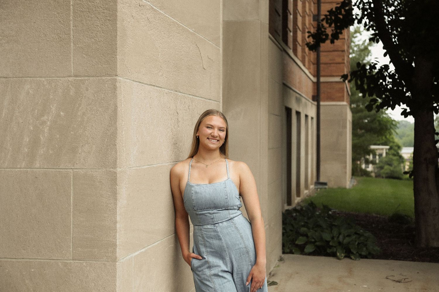 Casual poses against stone architecture in light denim outfit during outdoor photoshoot.
