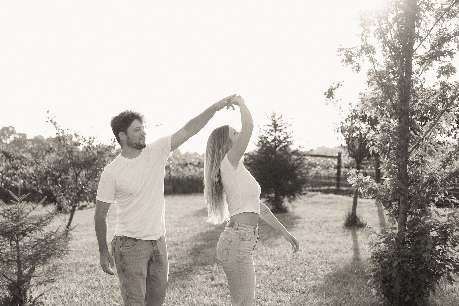 Romantic couple holding hands while walking through a sunny field.