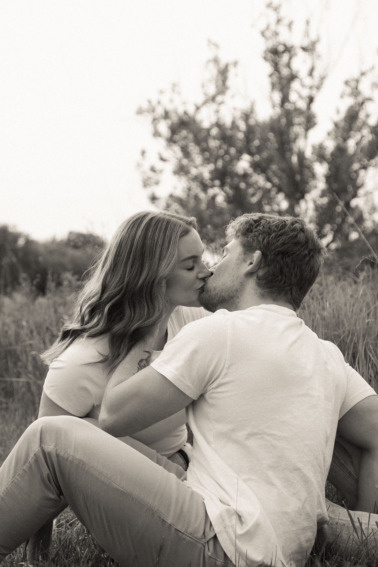 Romantic couple lying in grass together sharing intimate black and white moments.