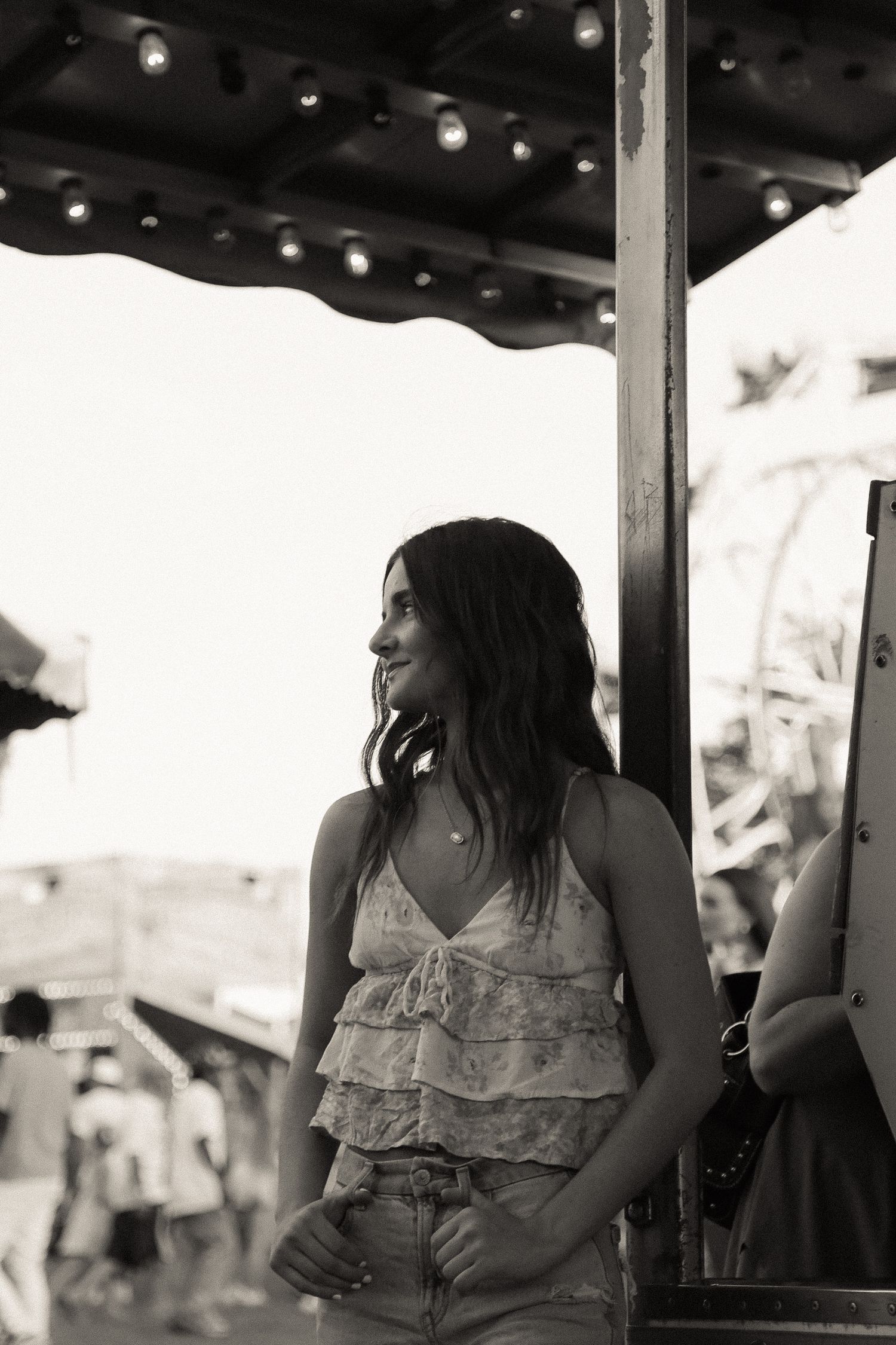 A casual summer scene under carnival lights with someone in a ruffled top.