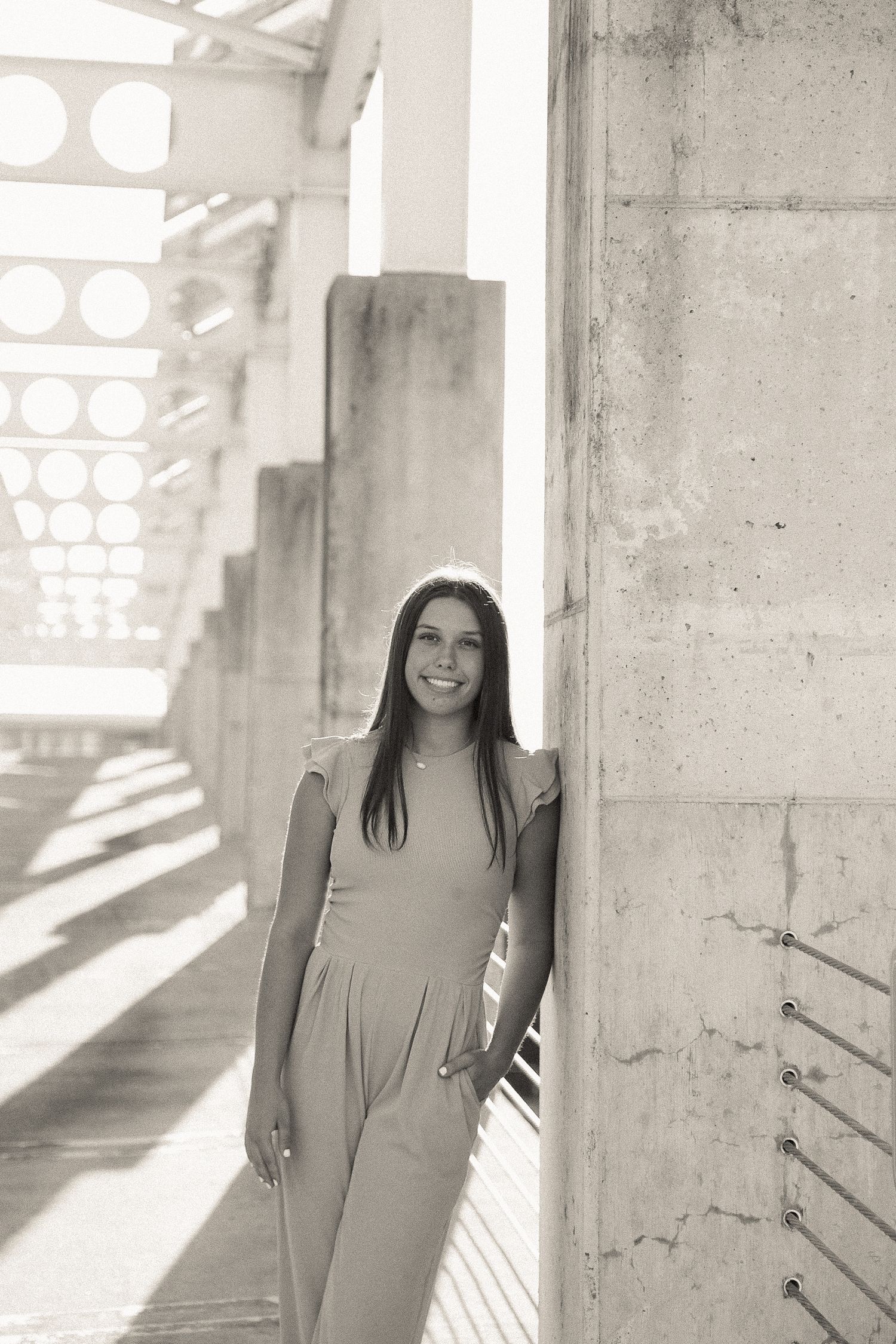 Monochrome fashion series captured in an architectural setting with dramatic lighting and concrete pillars.