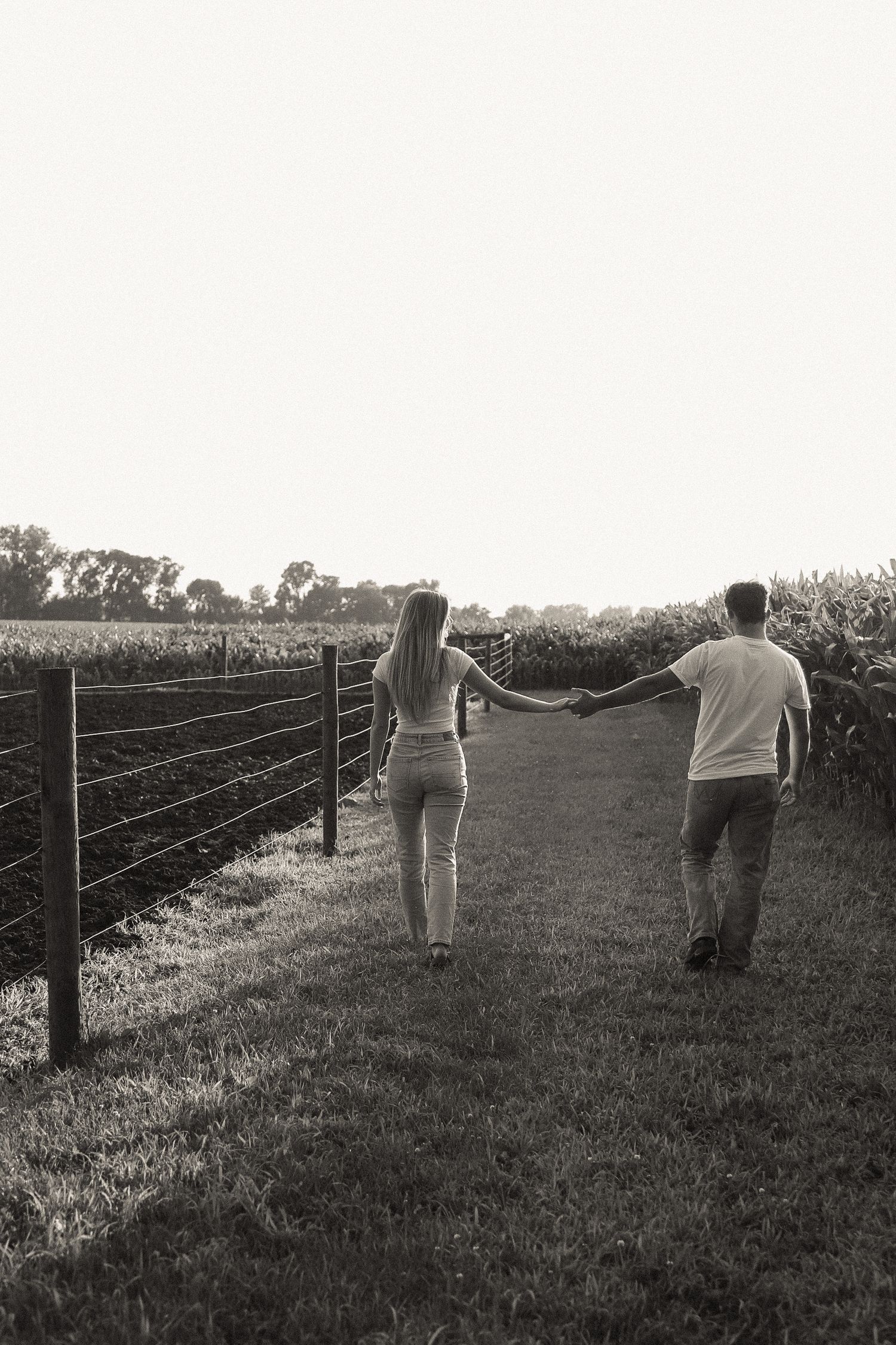 People walking along a rural fence line surrounded by farmland.