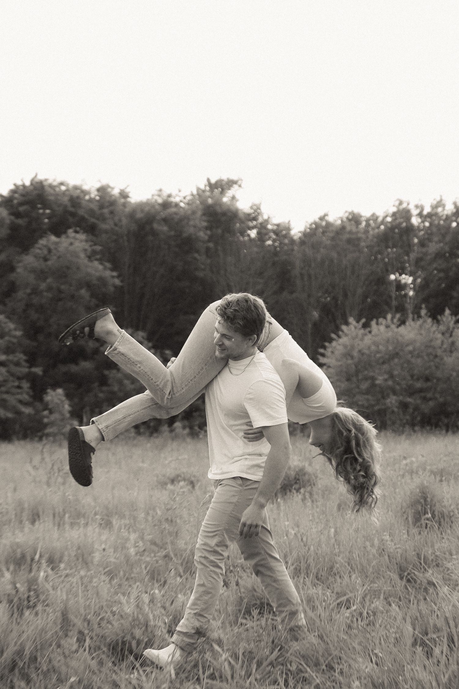 A playful moment captured as one person lifts another in a field.