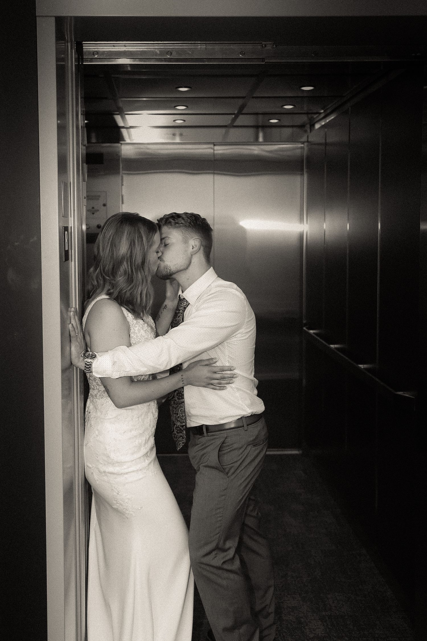 Couple in white clothing standing together in a dark hallway.