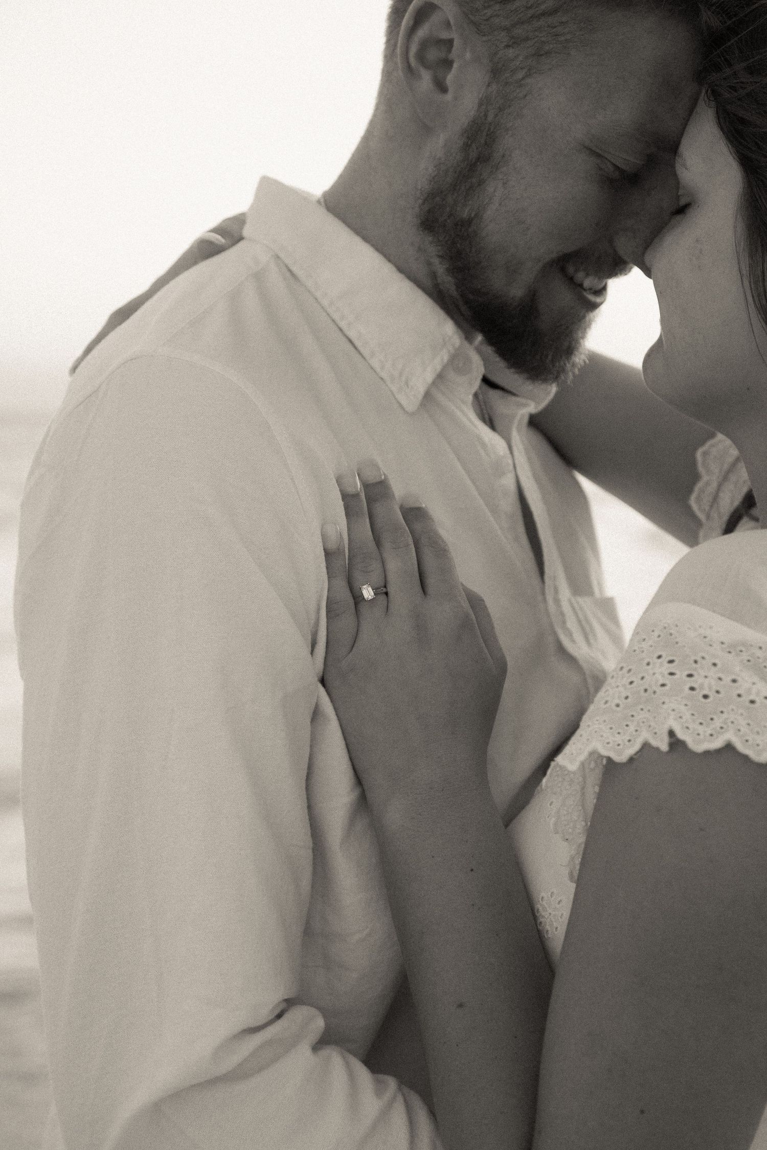 An intimate close-up portrait of a couple sharing a tender forehead touch in soft lighting.
