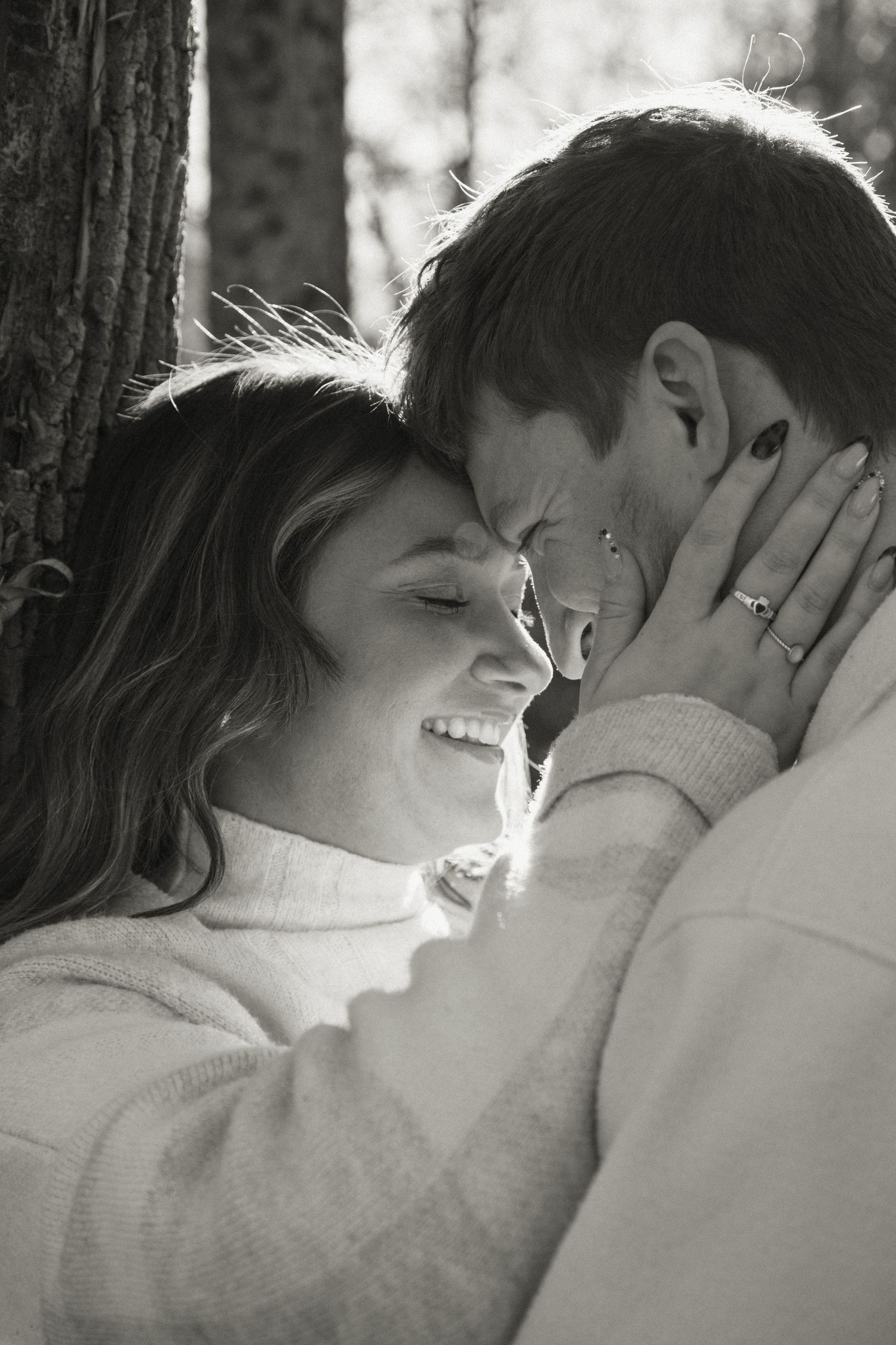 A black and white intimate portrait of a couple sharing a close moment in nature.