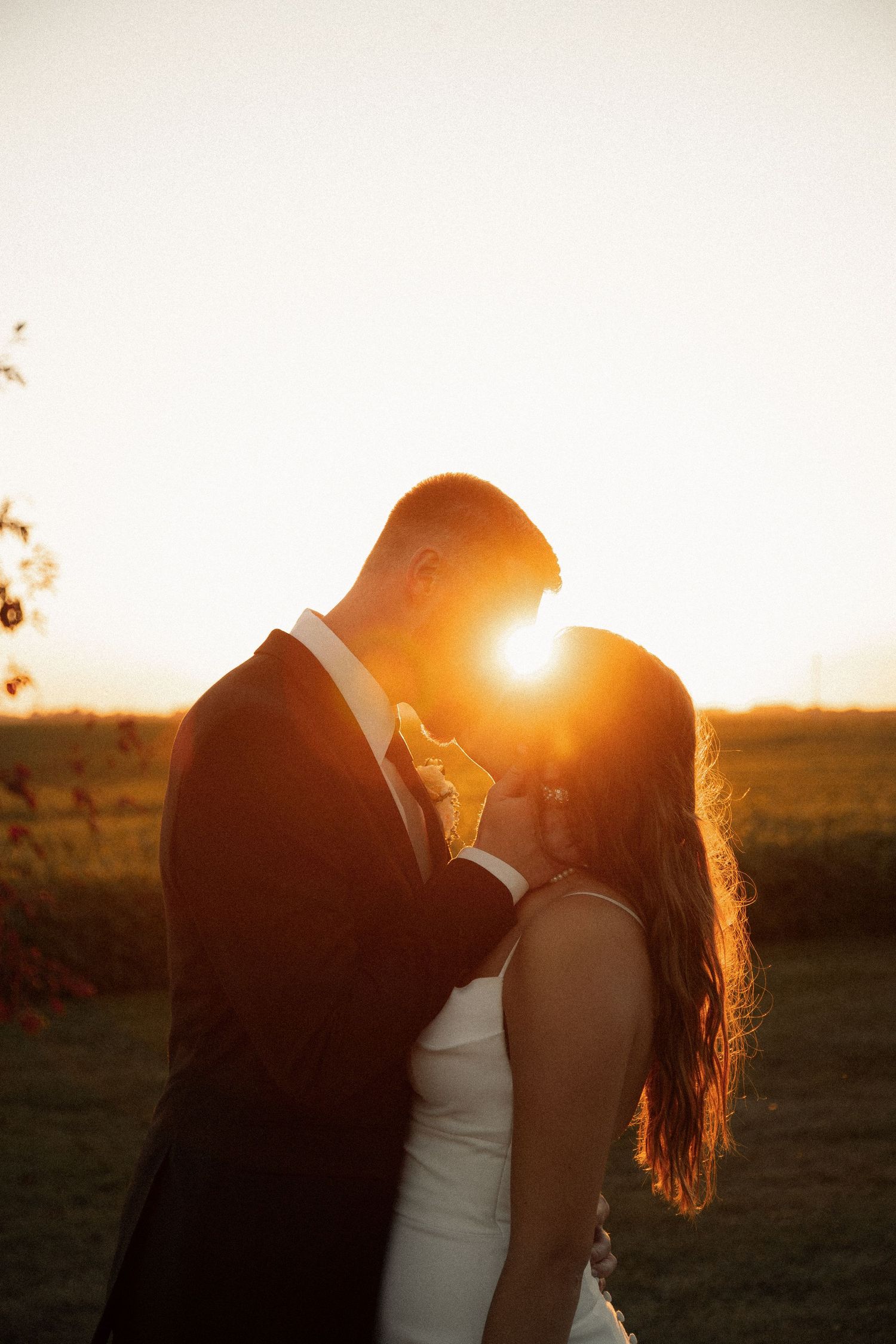 Newlyweds share a tender moment with sun flare creating a magical golden hour atmosphere.