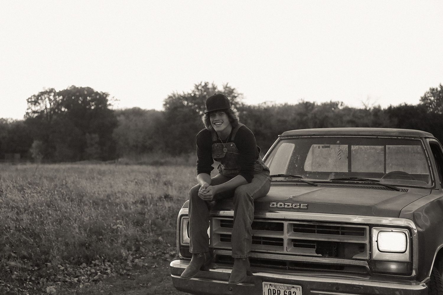 Vintage Dodge car parked in a rural field at sunset.