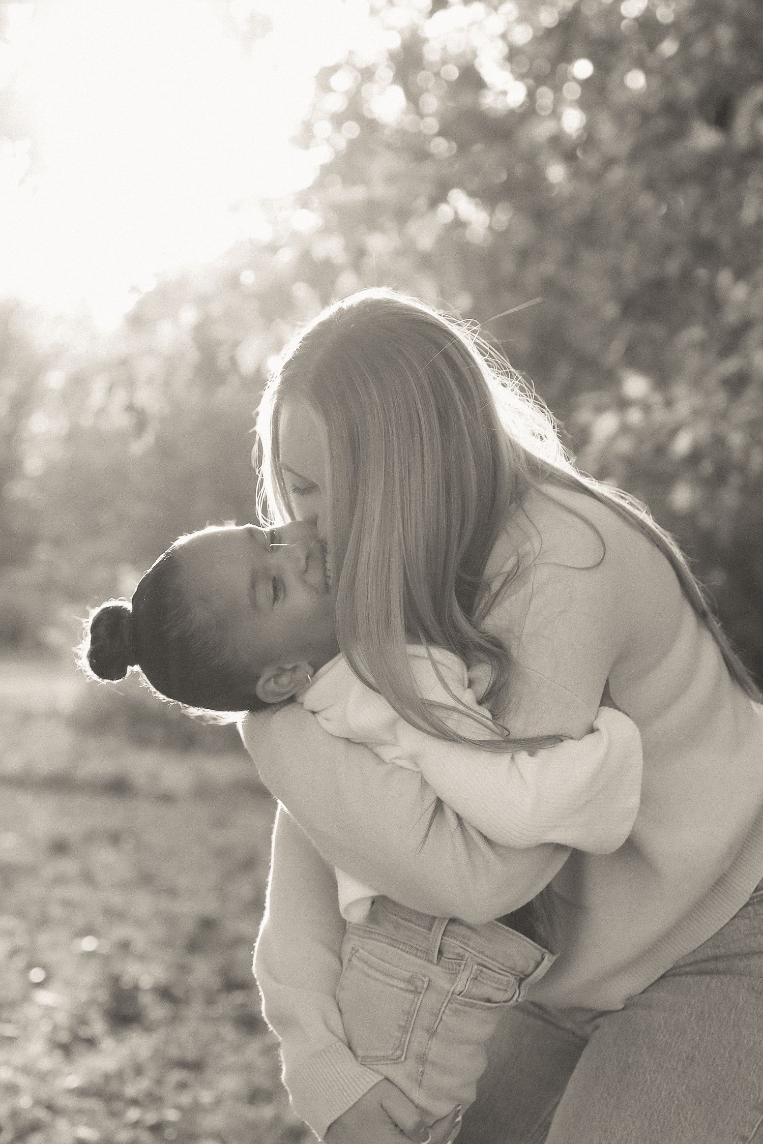 A tender moment between parent and child captured in black and white photography outdoors.