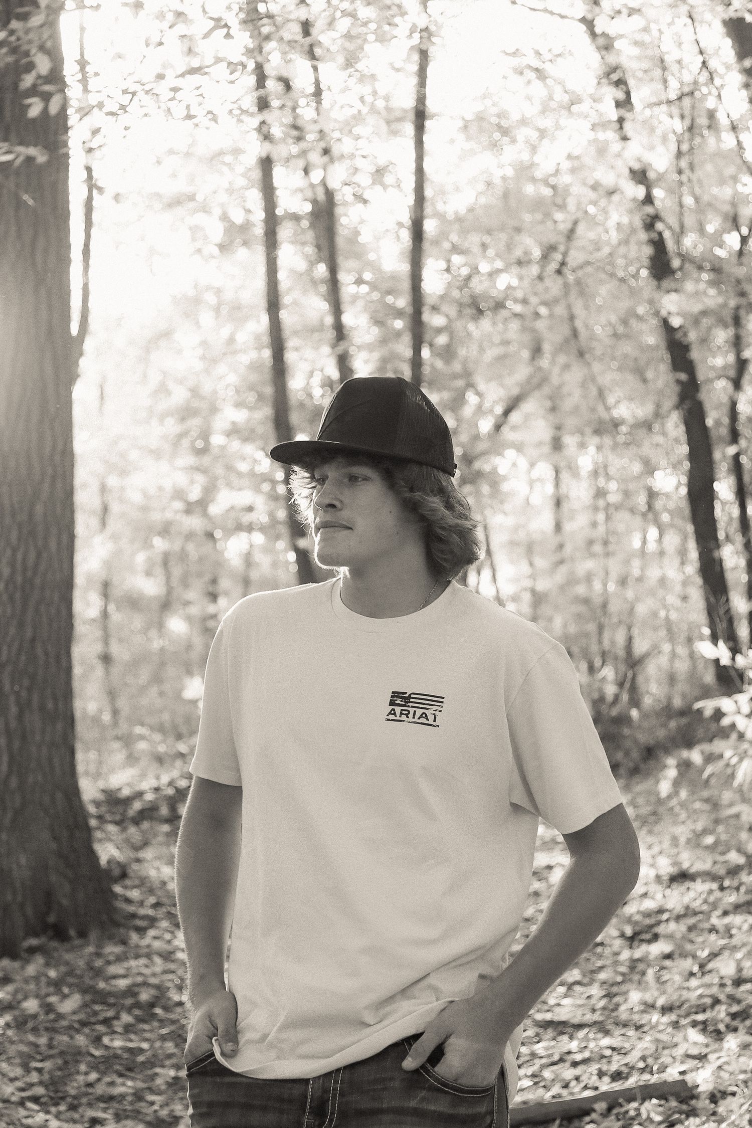 Natural portrait series against autumn forest backdrop wearing white t-shirt and baseball cap.