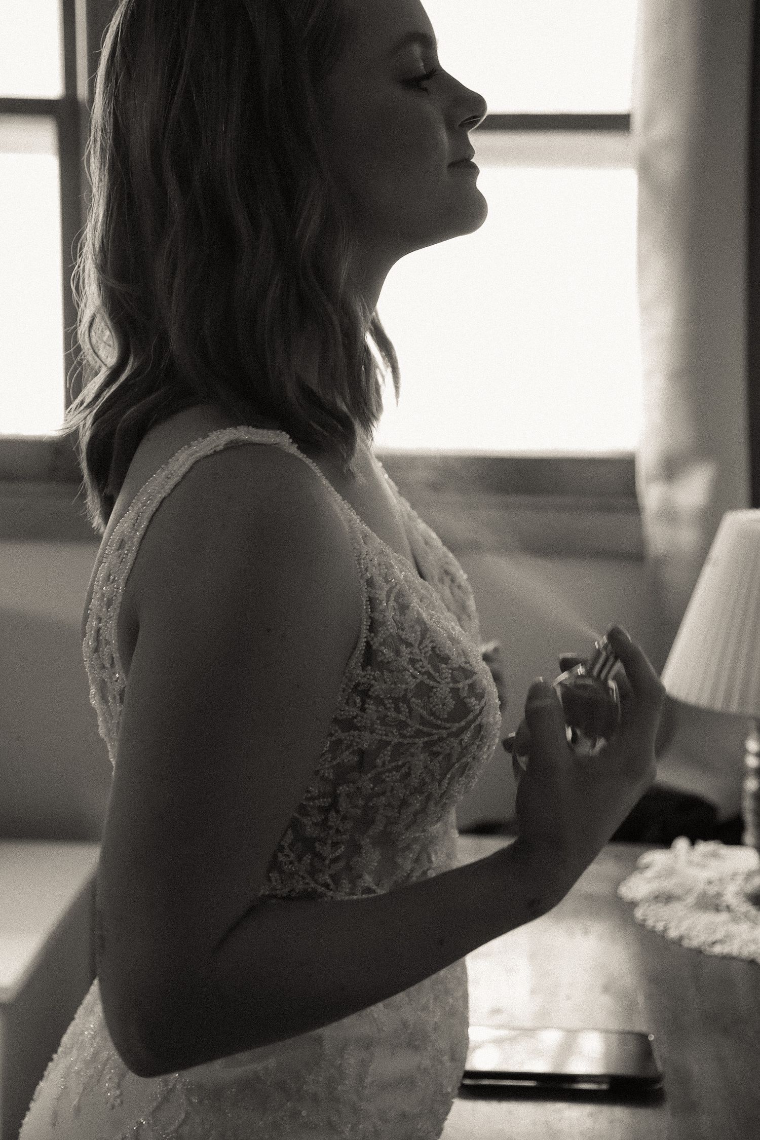A silhouette of someone in a lace wedding dress against a bright window.