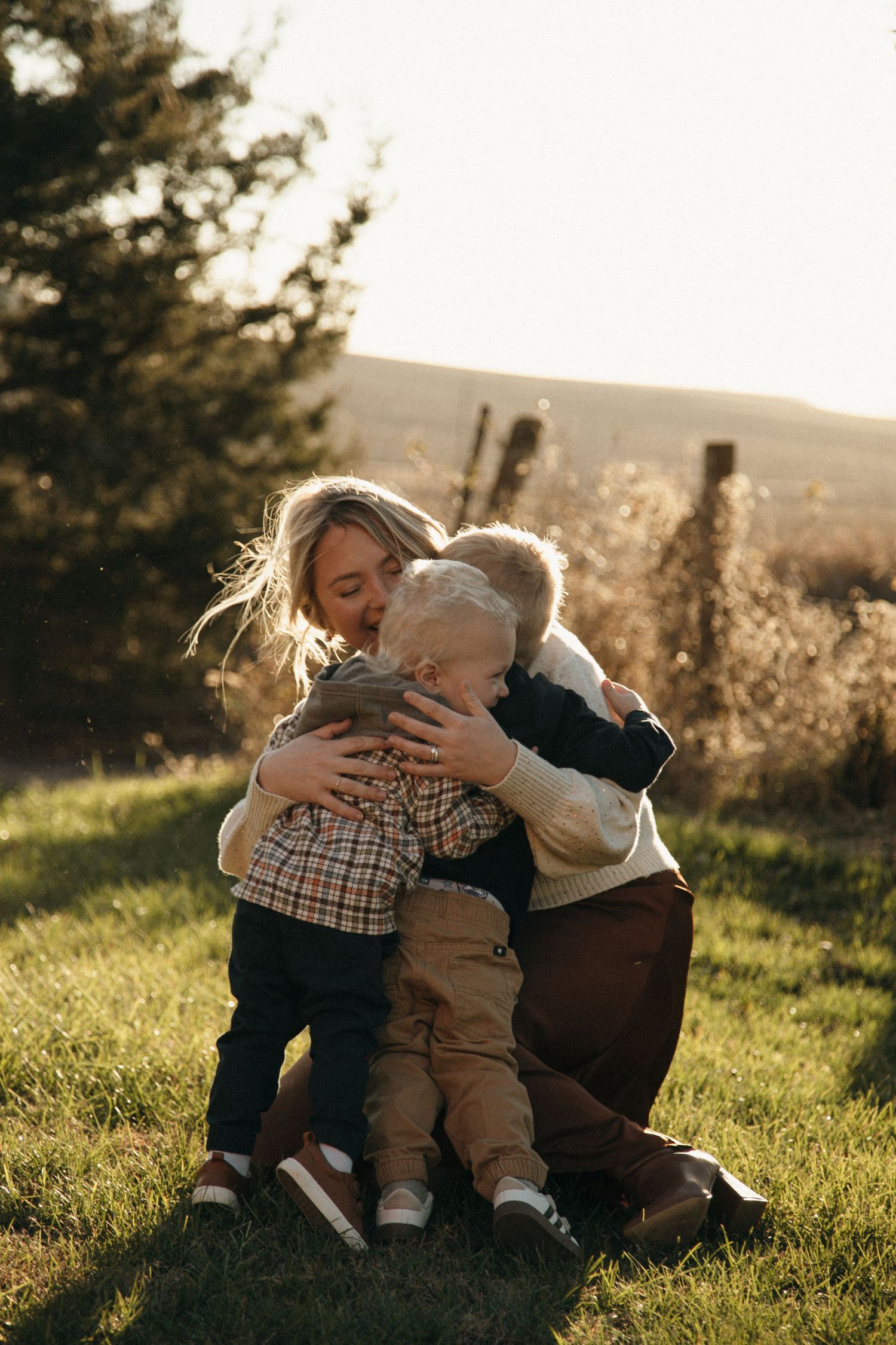 Intimate family moment shared on grassy hillside during sunset.