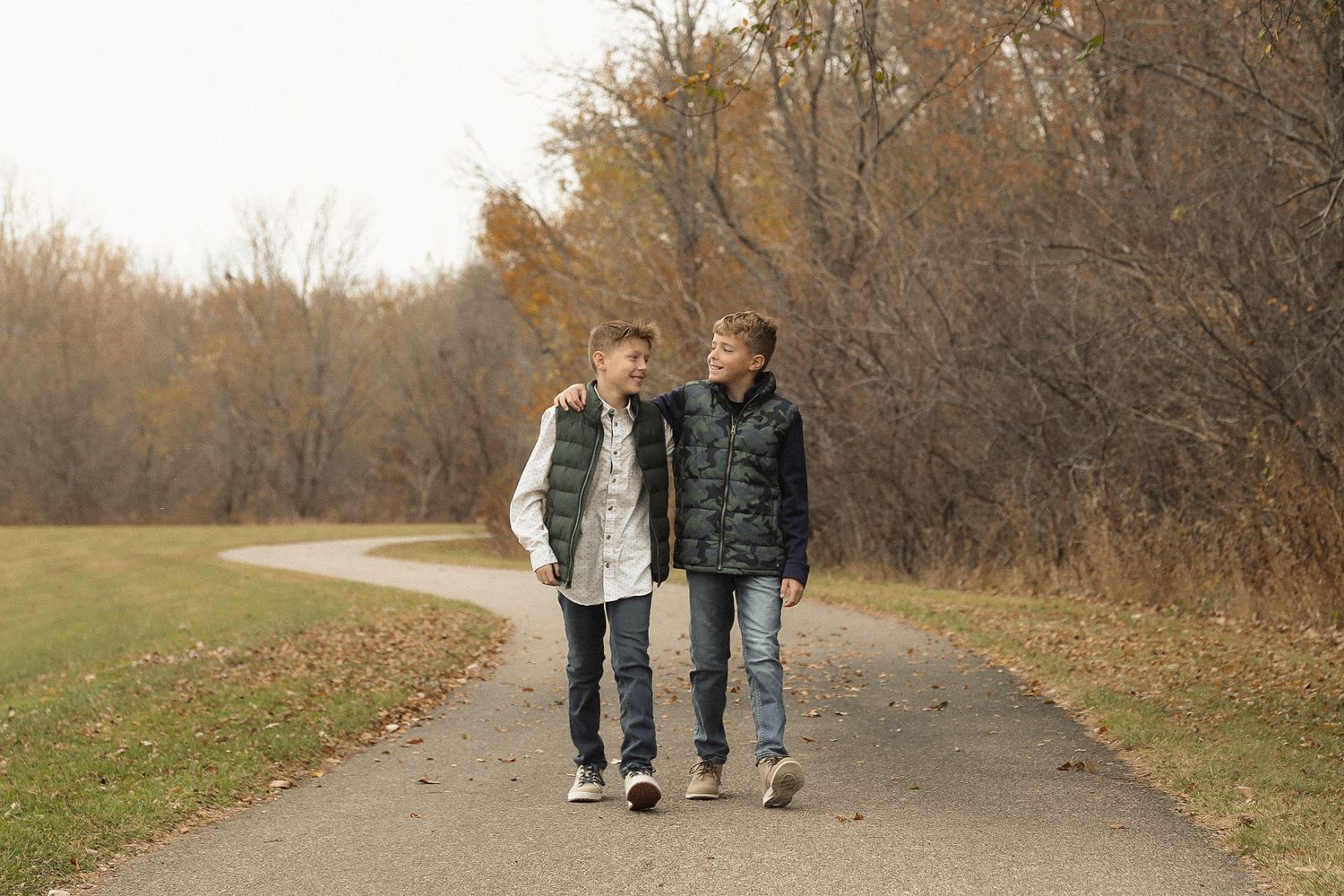 Family members walking together on an autumn path surrounded by bare trees.