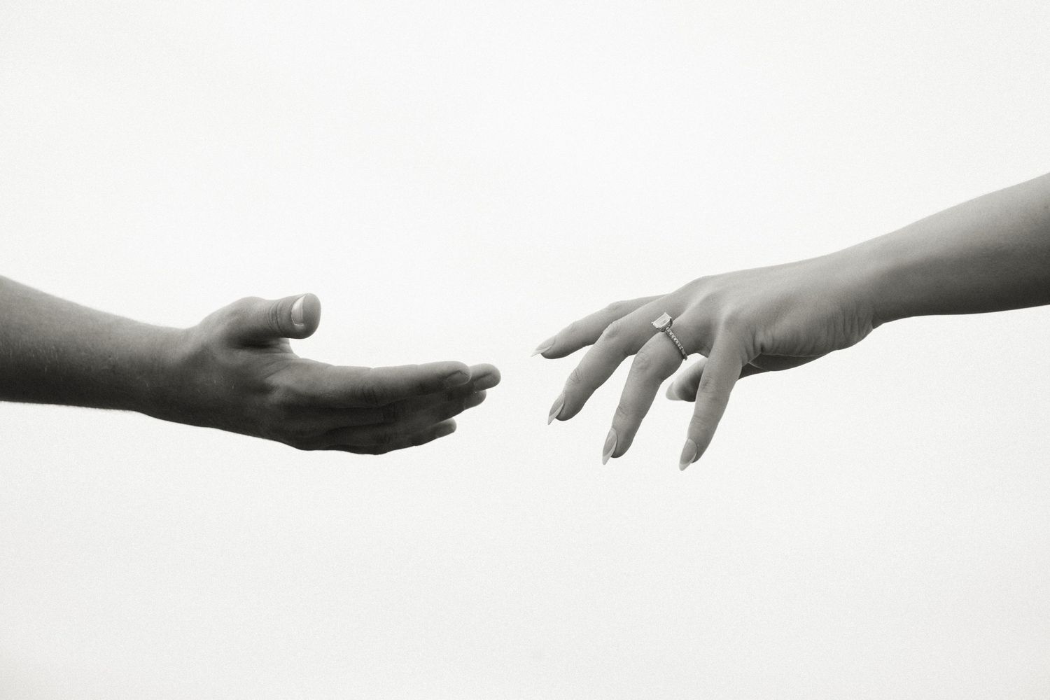 Two hands reaching toward each other in black and white, symbolizing connection, help, and human touch.