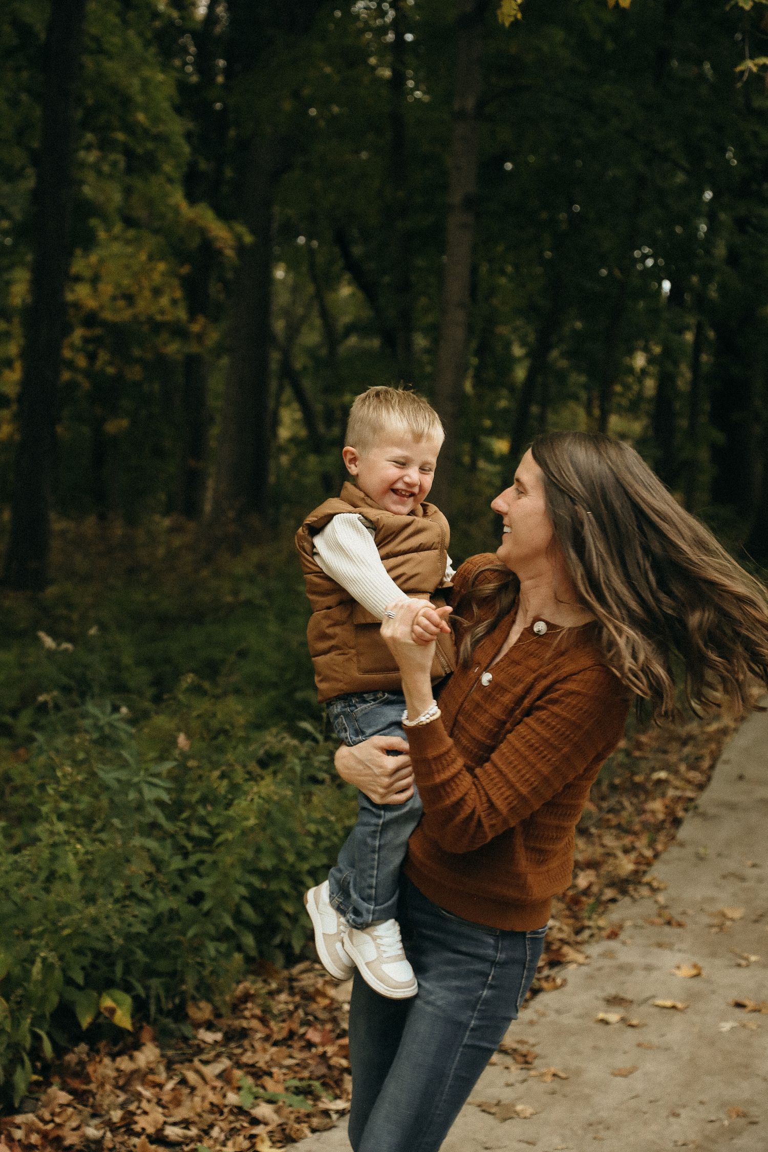 A joyful moment of play and laughter in a wooded setting during fall.