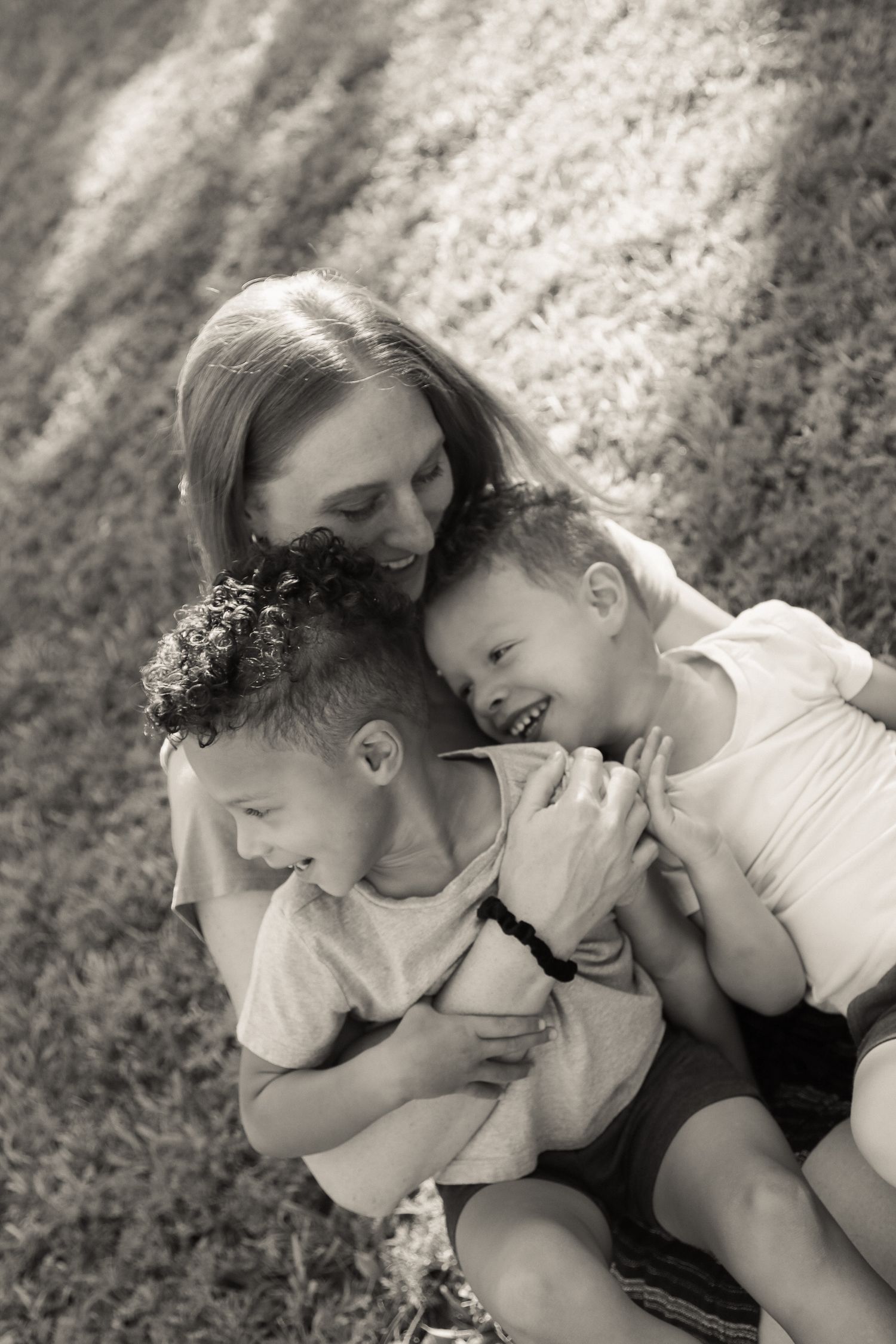 Candid black and white sequence capturing playful family moments on the grass.