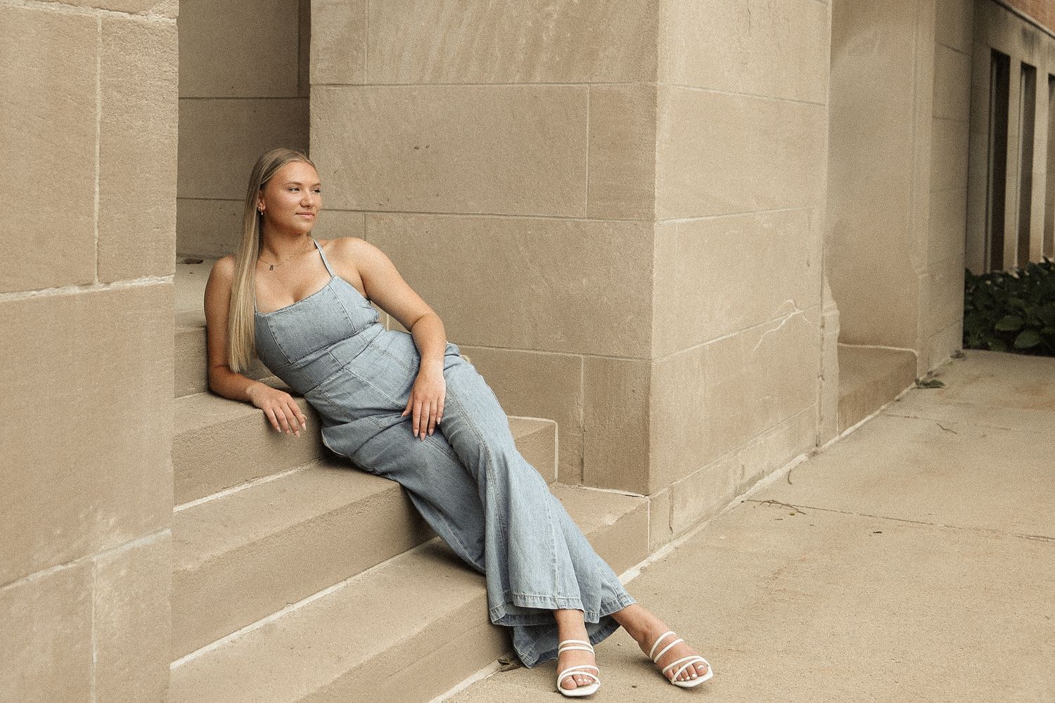 A relaxed pose on stone steps in casual denim attire.