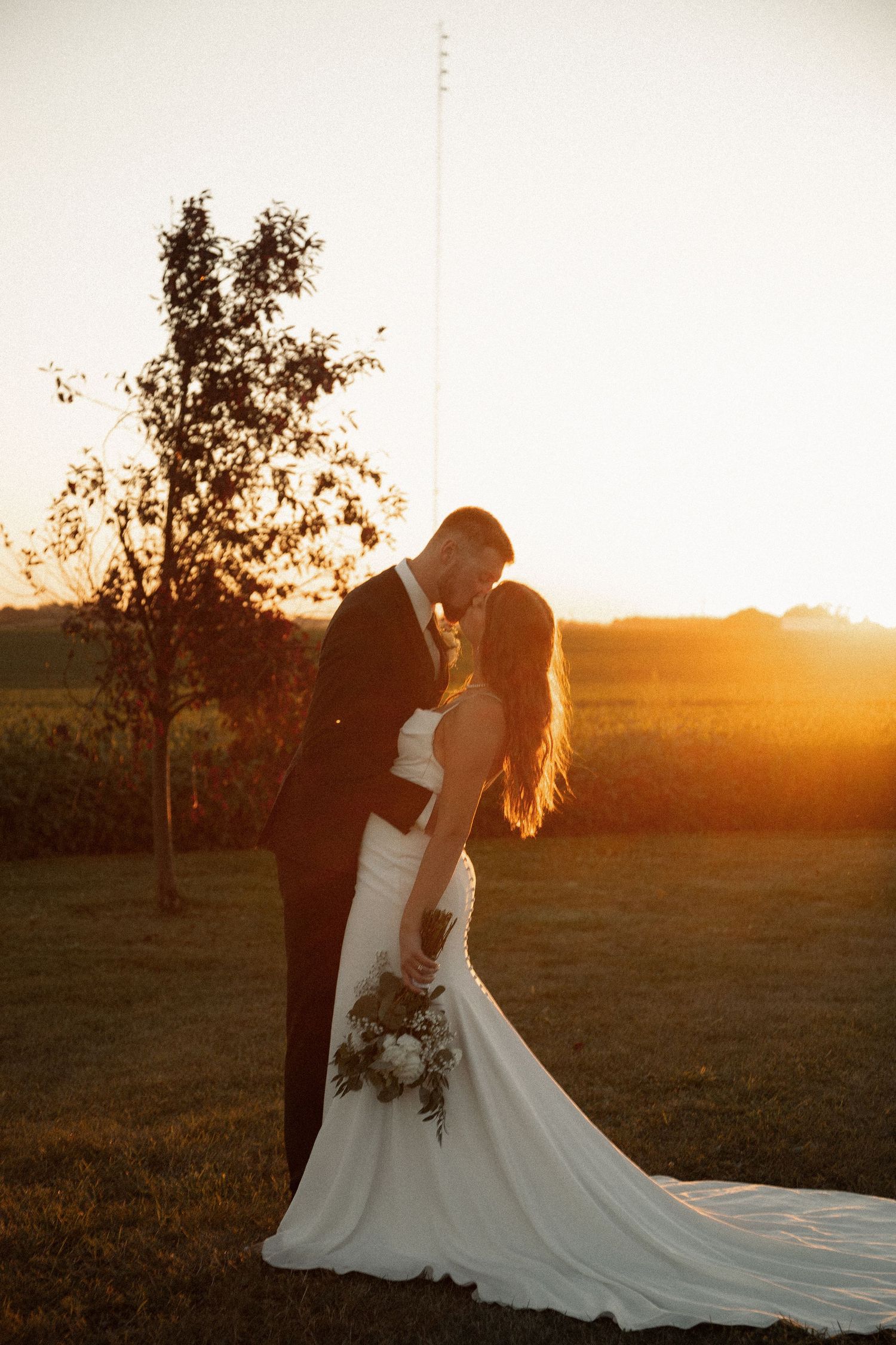 A romantic sunset wedding portrait with the couple sharing an intimate moment against a golden sky.
