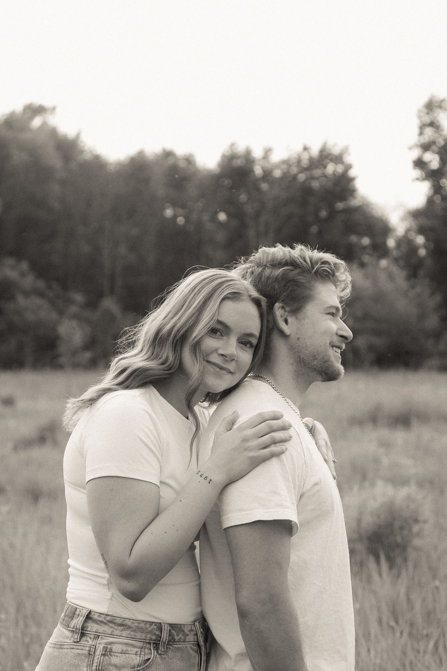 A couple shares a tender moment together in a sunny field.