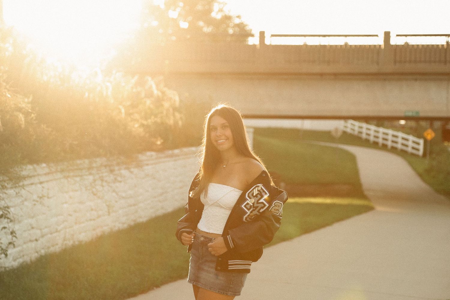 Golden hour portrait session with sun flare and fence elements in background.