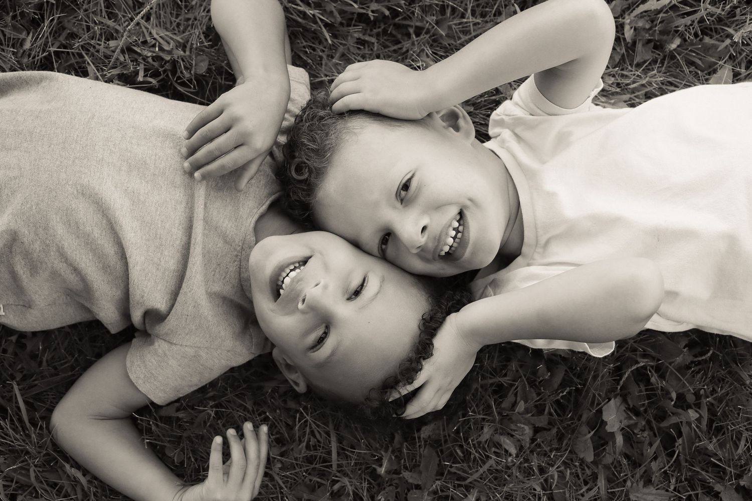 Series of candid black and white shots showing playful moments lying in grass.