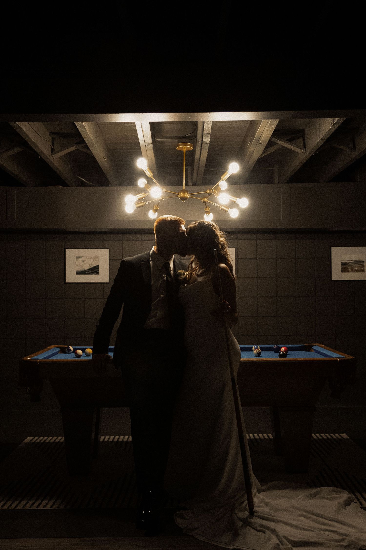Dimly lit room with pool tables and hanging lights creating an atmospheric scene.