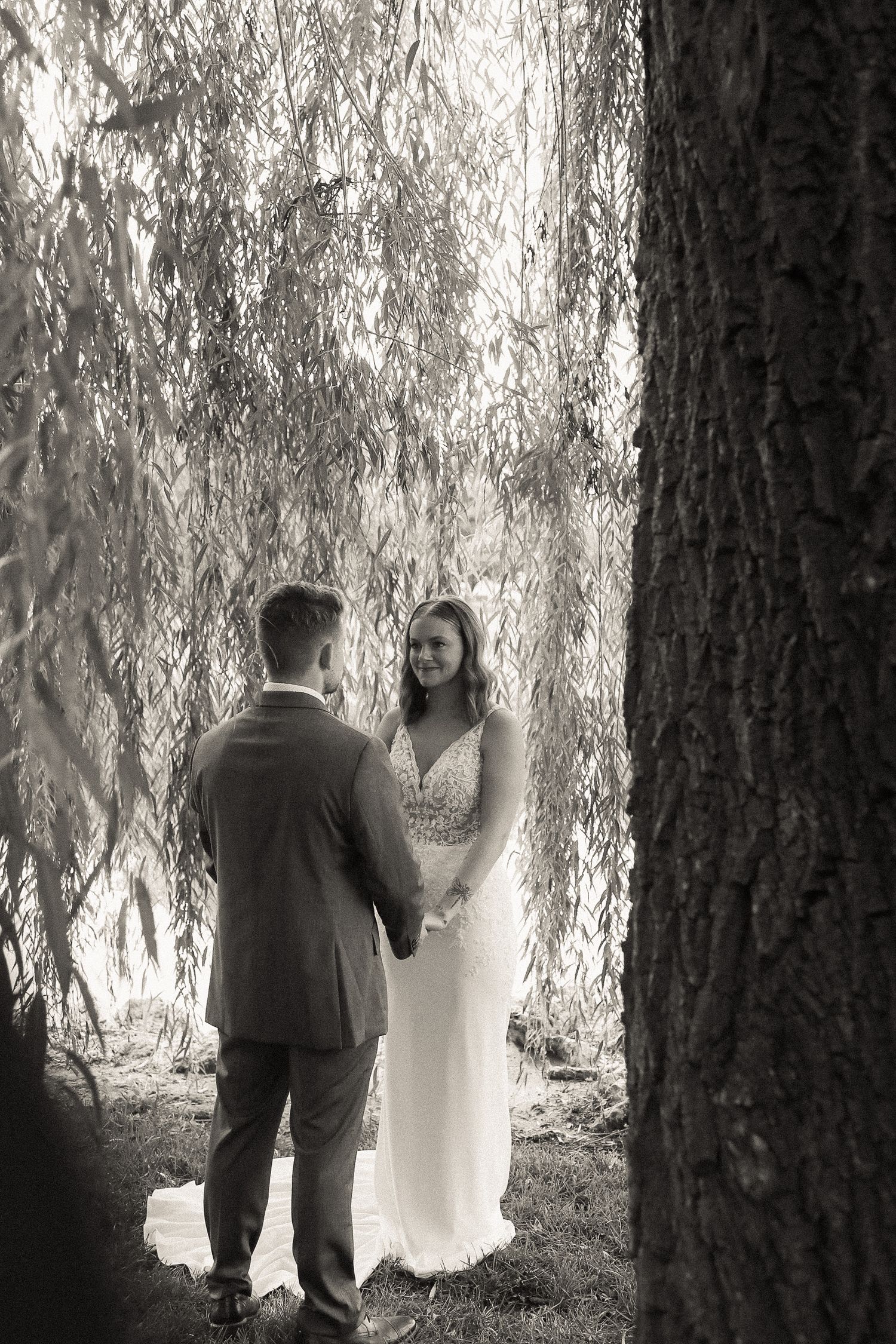 A romantic moment between a couple under a weeping willow tree.