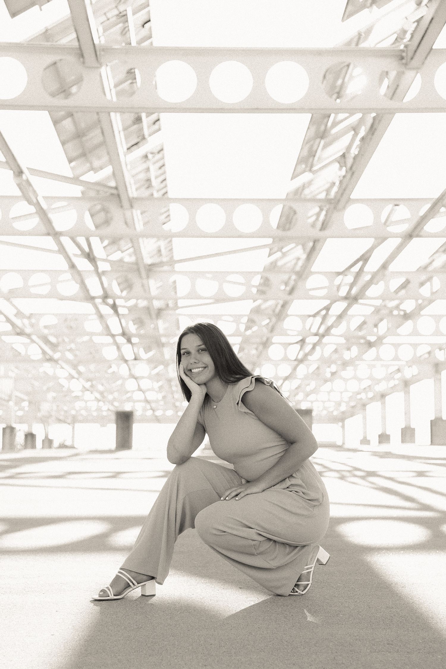Artistic black and white photo series showing a person in casual attire lounging on a bright industrial floor.