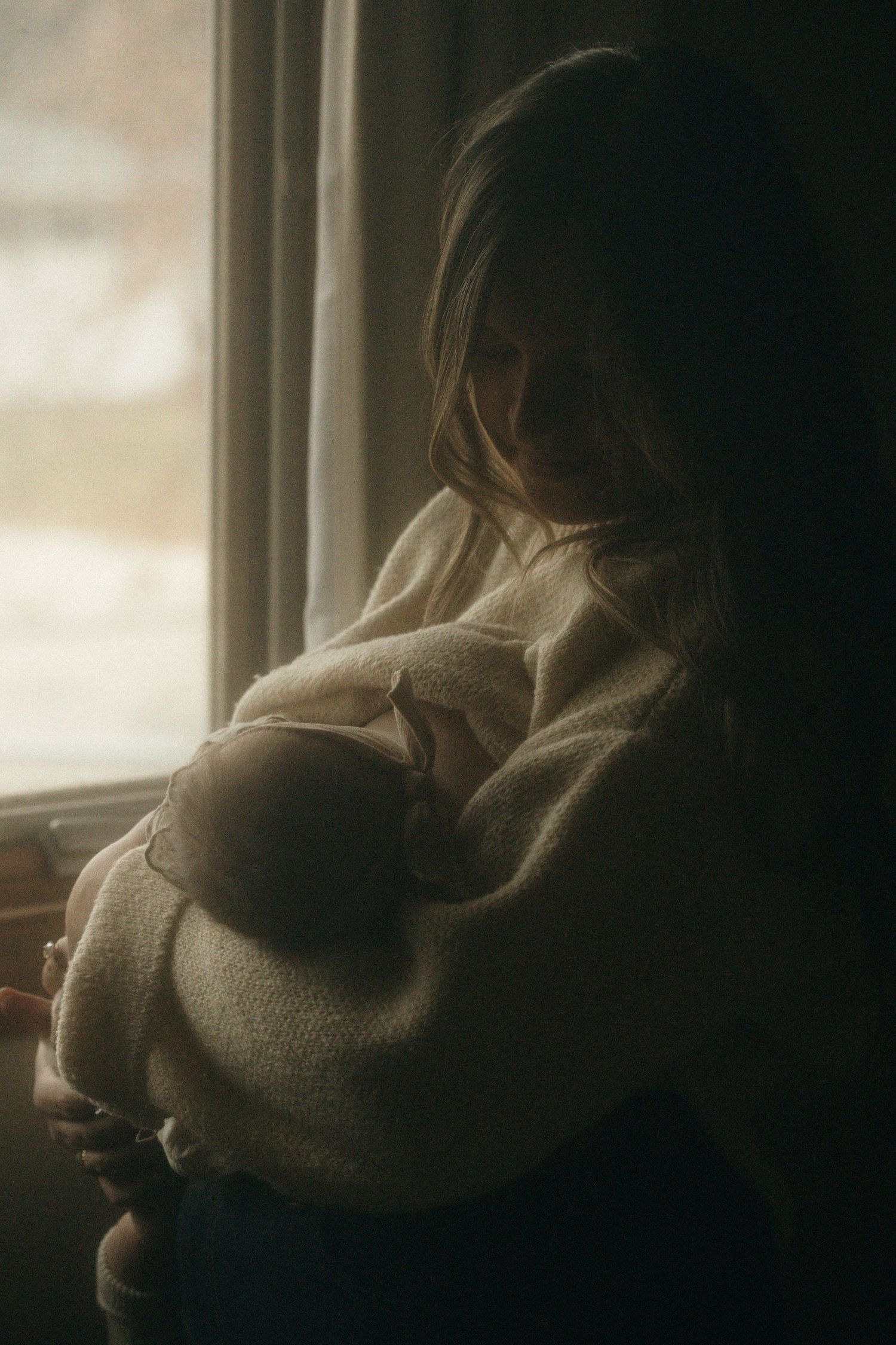 Moody window light creates dramatic shadows in a quiet indoor moment.