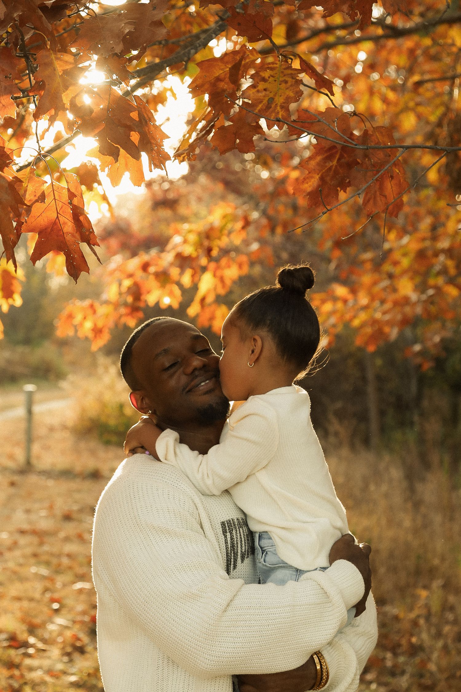 A heartwarming embrace between parent and child under golden autumn leaves.