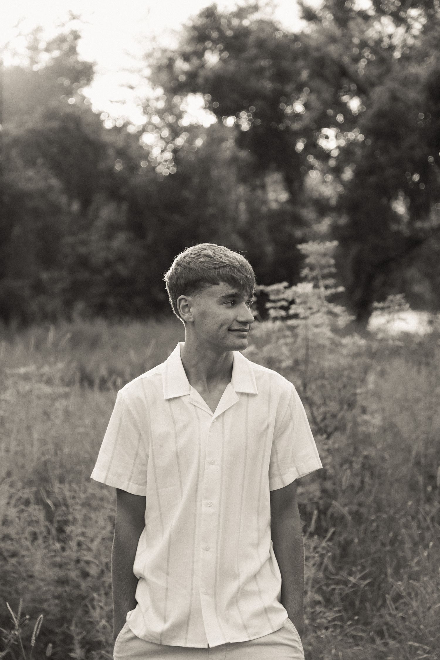 Person in white shirt poses in field during golden hour photography session.