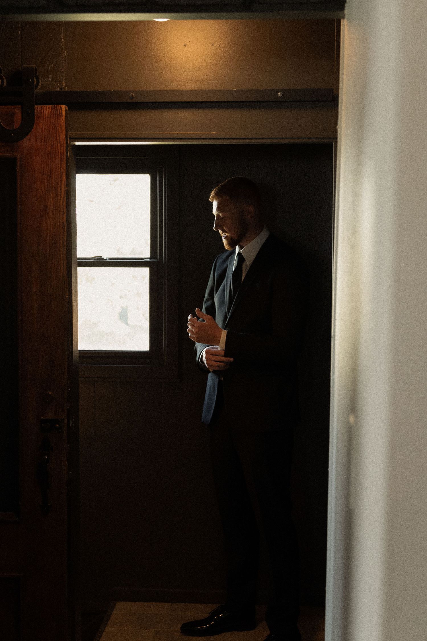 A dark hallway with dramatic lighting and a silhouette standing near a window.