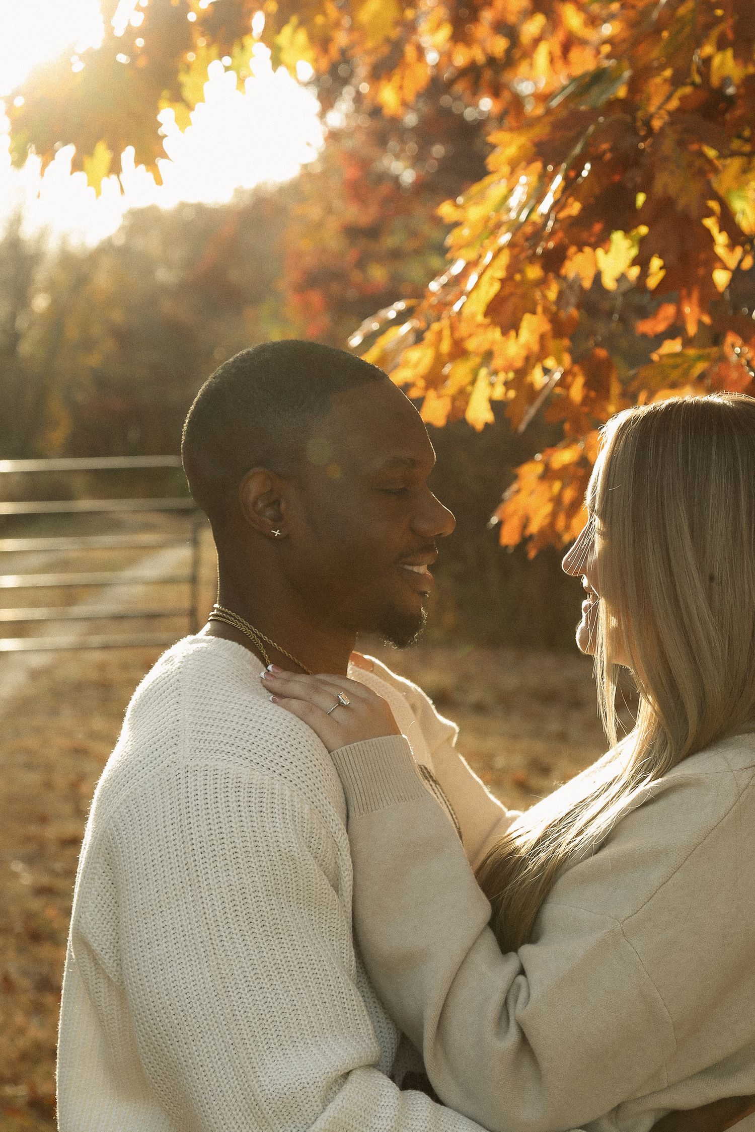 Couple sharing tender moments under golden autumn leaves at sunset.