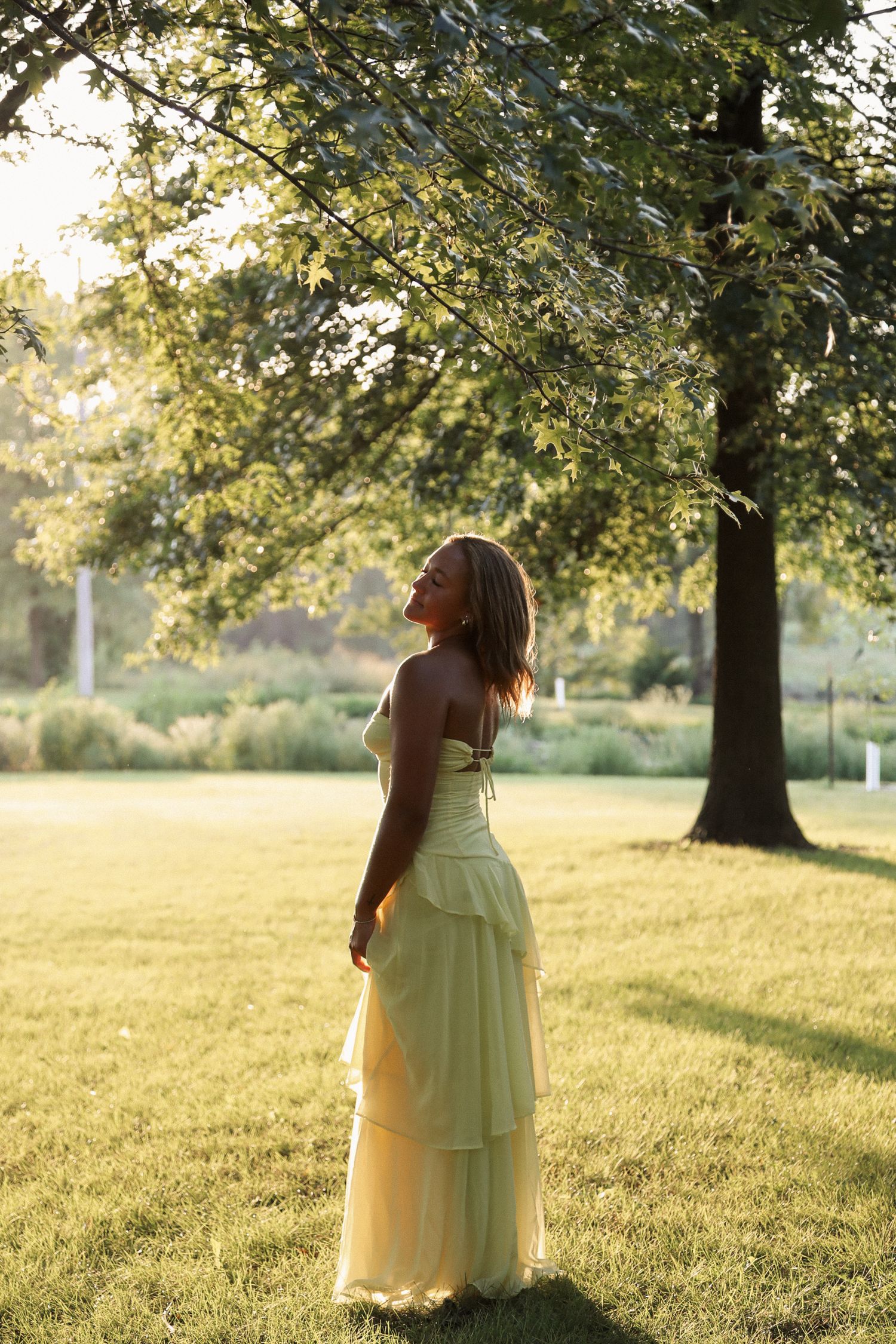 Person in flowing dress twirls in a sun-dappled meadow during golden hour.