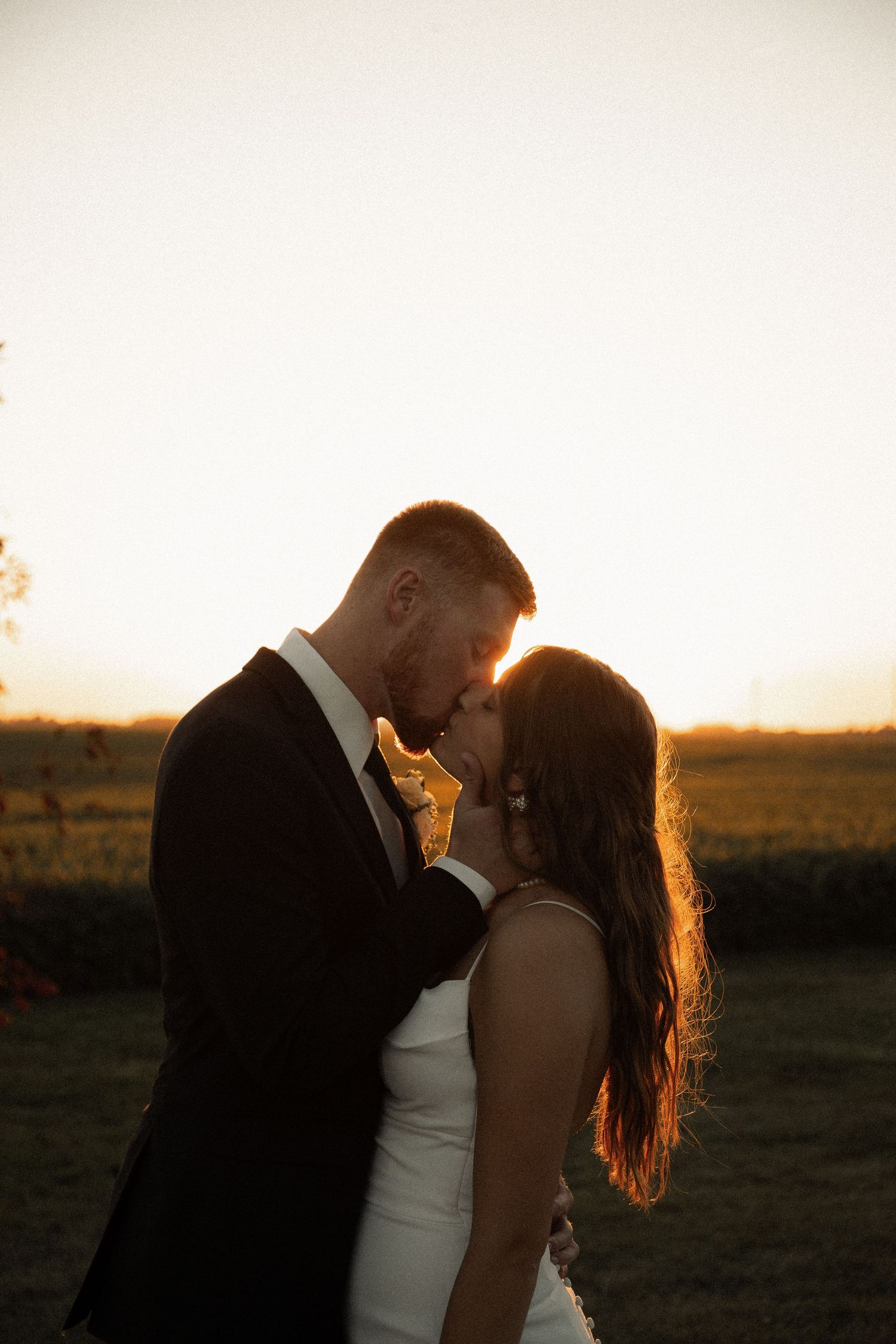 A romantic sunset wedding portrait showing an intimate embrace against golden evening light.