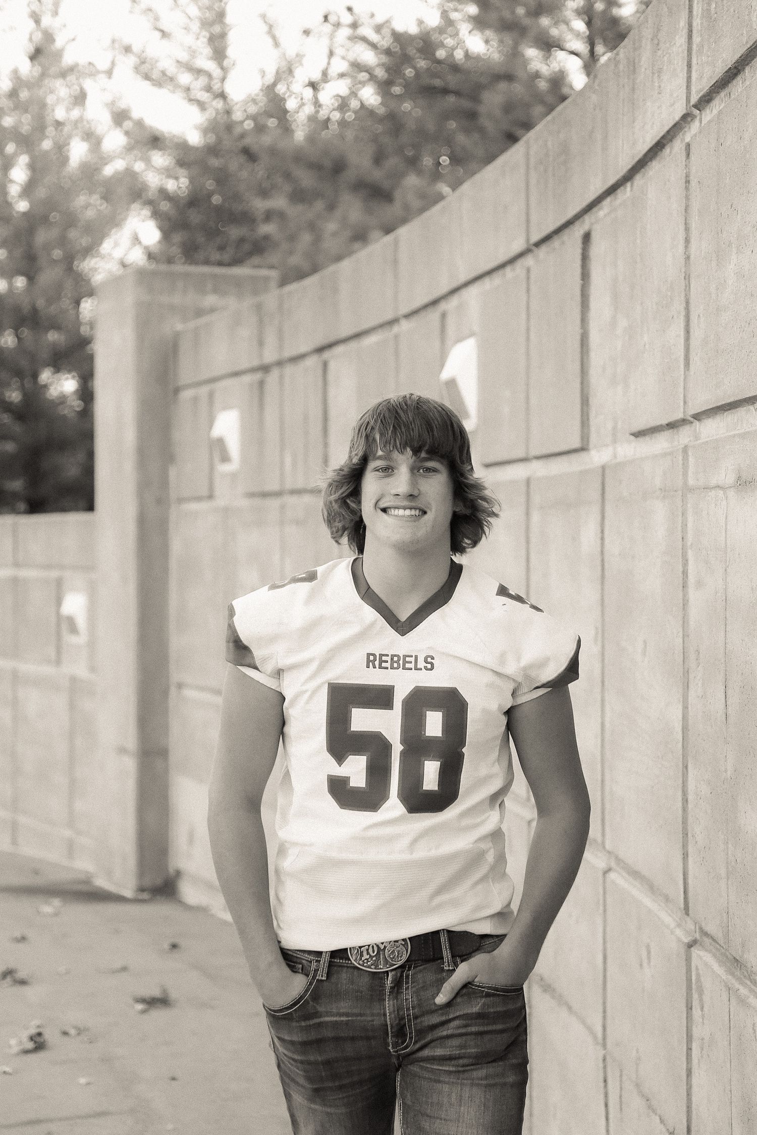 Person wearing a Rebels jersey number 58 poses against a concrete wall in black and white.