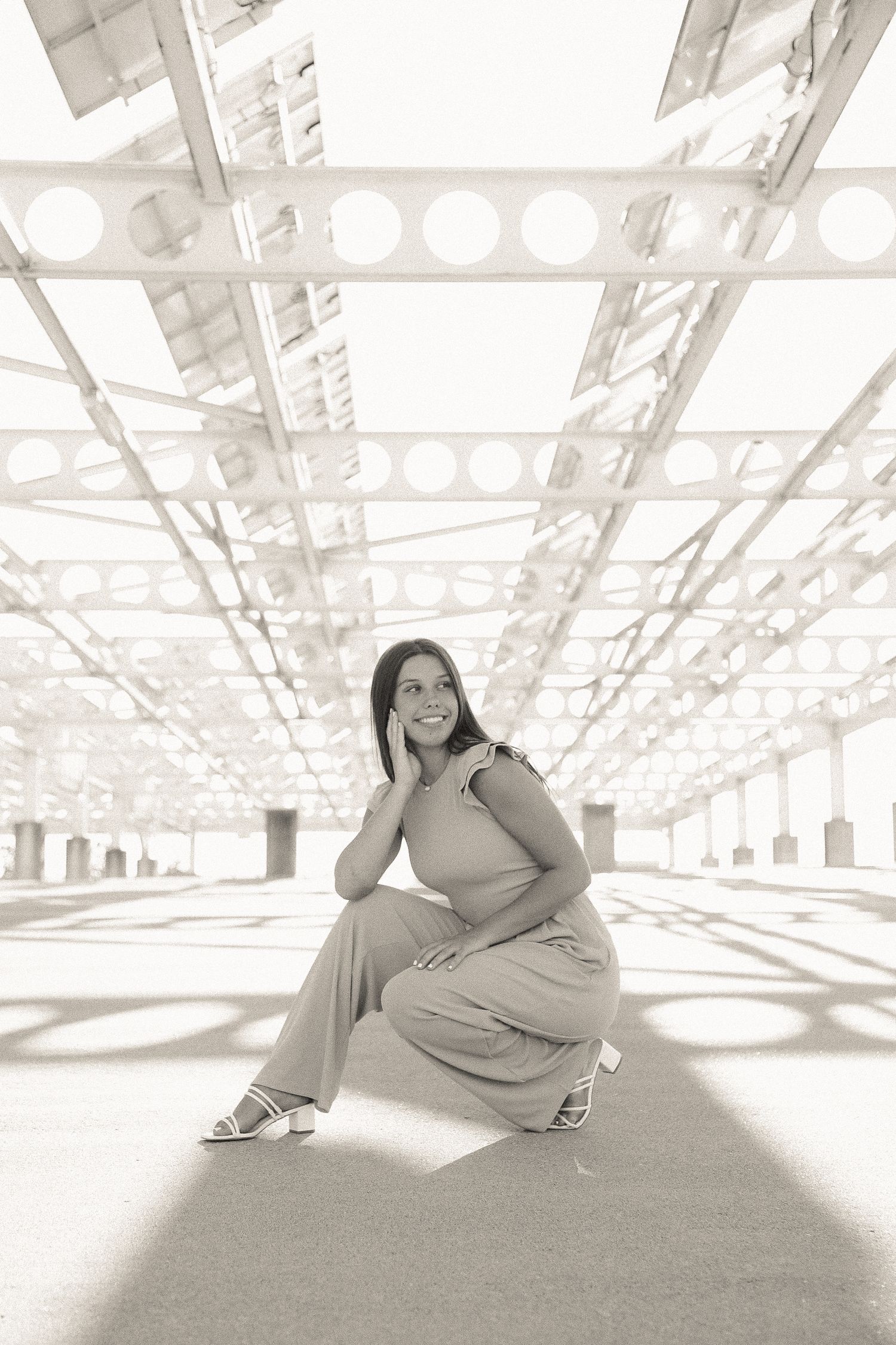 Black and white portrait series showing relaxed poses against an industrial backdrop with natural lighting.