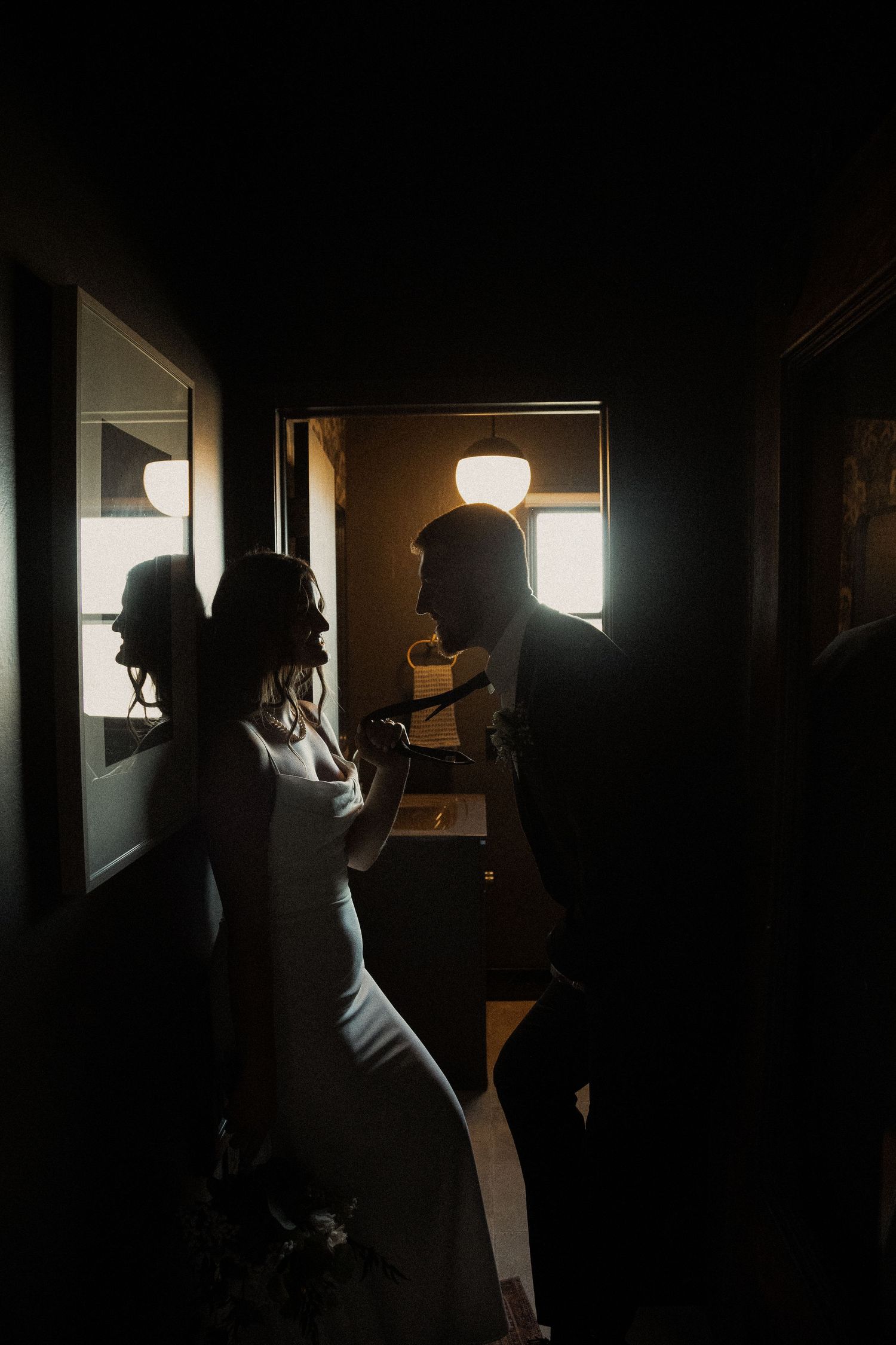 Dramatic silhouettes in a dark hallway with natural light streaming through windows.