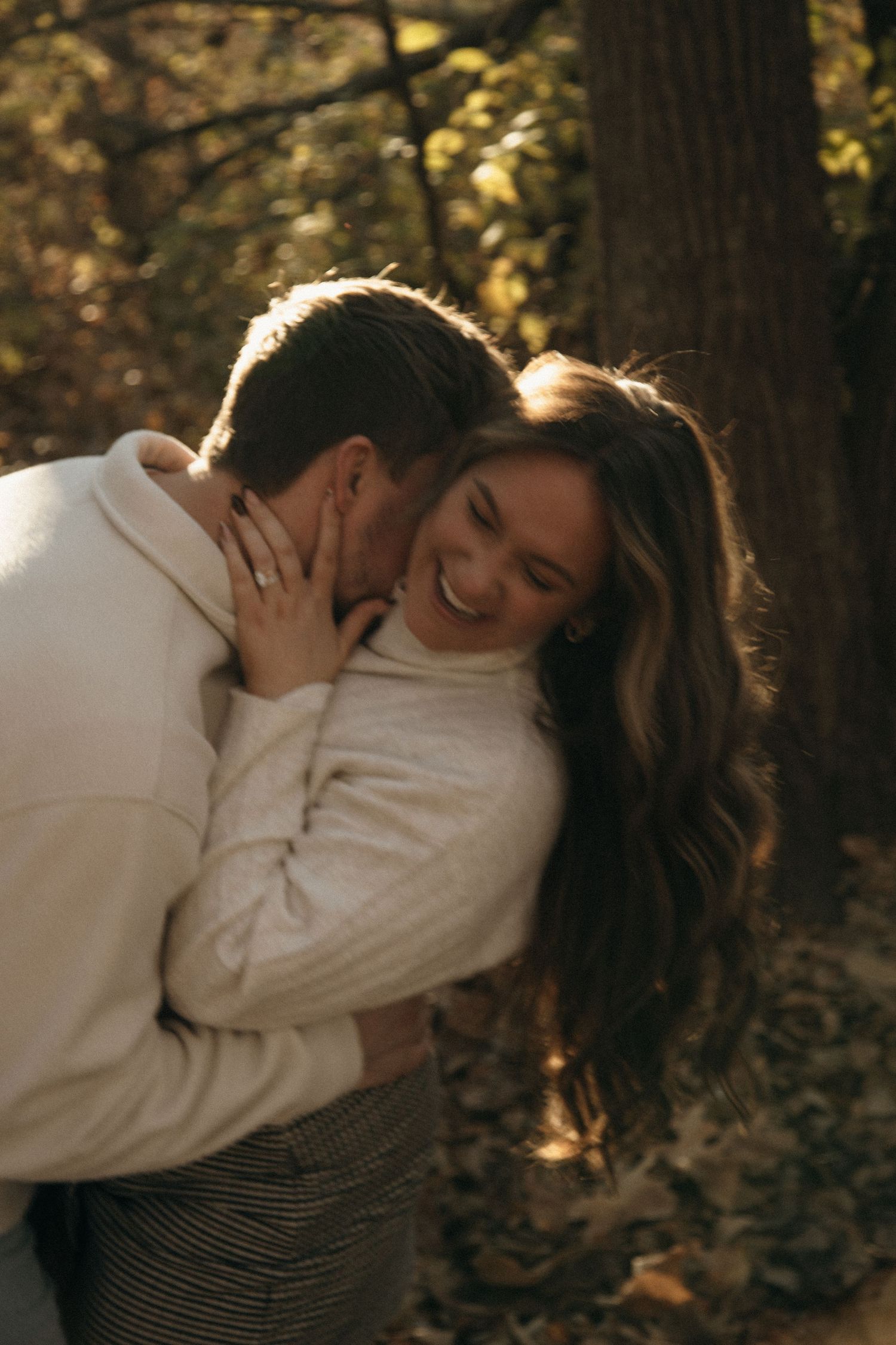 Couple in white and stripes share intimate embraces in a wooded autumn setting.