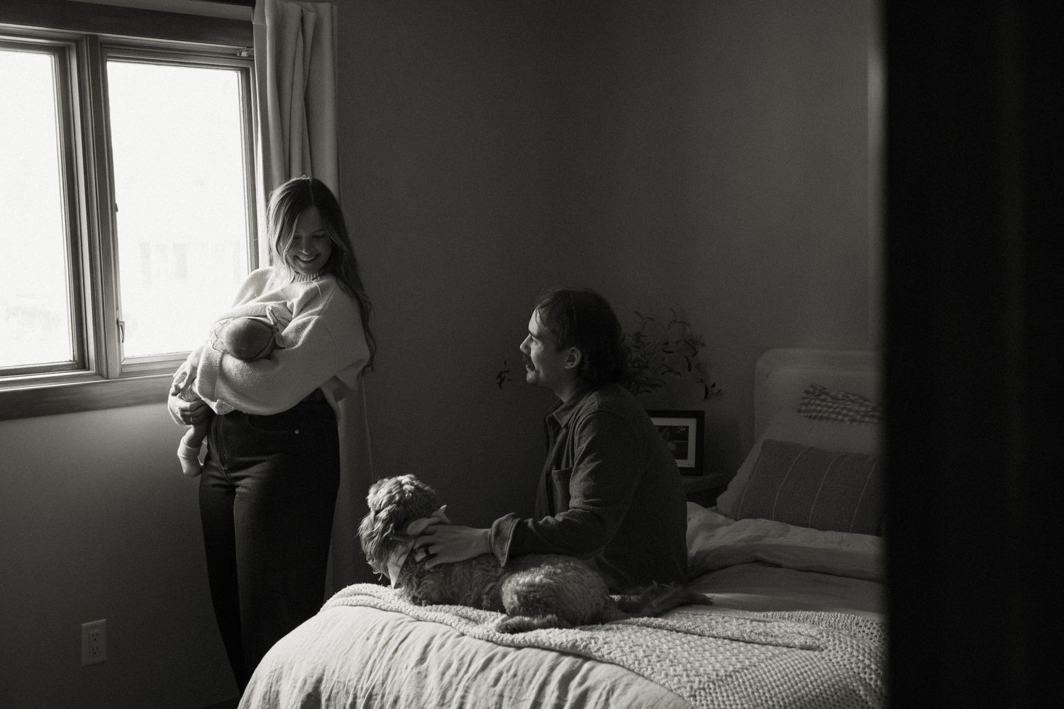 Moody indoor photography session with window light casting shadows in a bedroom setting.