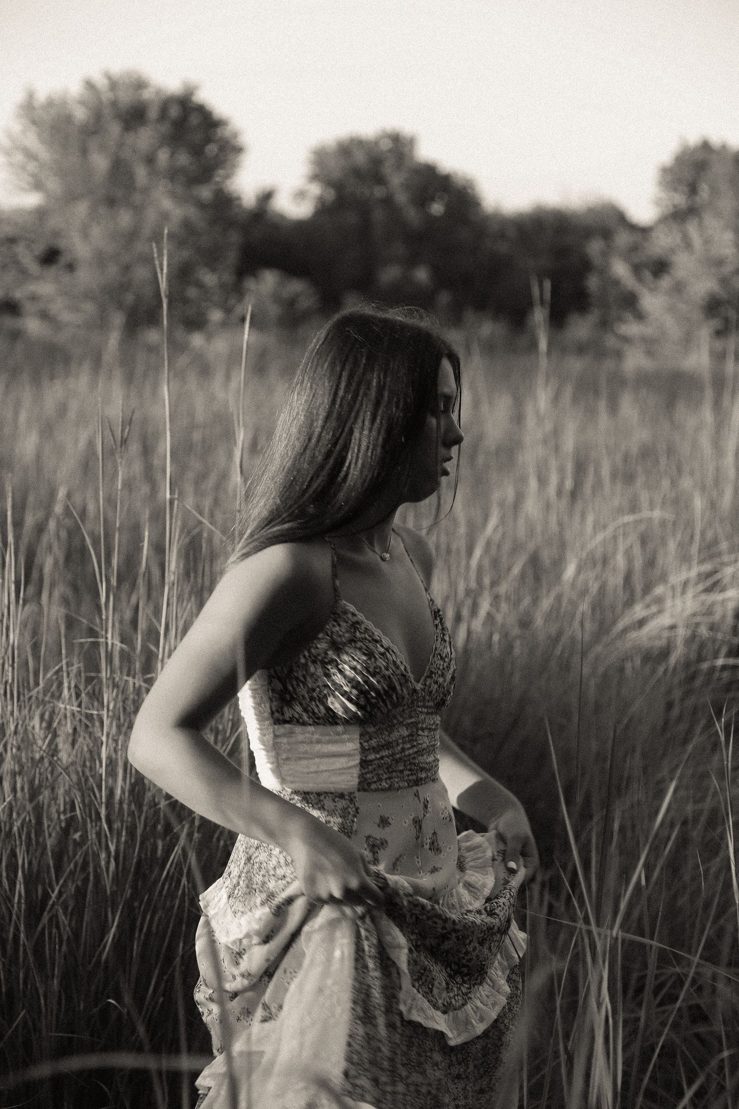 A flowing dress moves gracefully through tall grass in a dramatic black and white nature scene.
